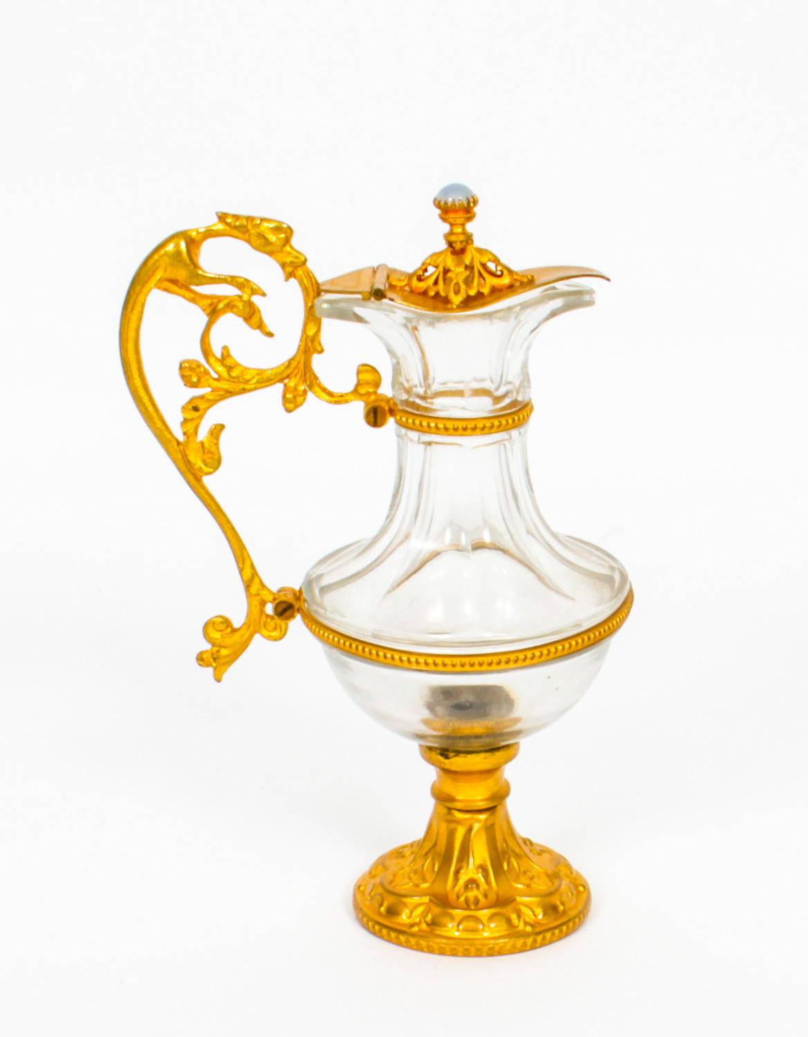 Il s'agit d'une superbe paire d'aiguières anciennes en verre doré, datant d'environ 1870.
Les couvercles à charnière sont ornés de fleurons en pierre semi-précieuse de type cabouchon et de poignées en forme de bêtes mythiques. Les corps en verre