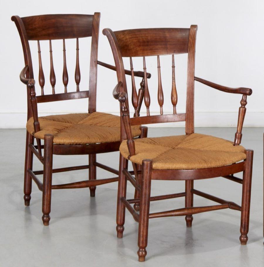 Late 19th c., a pair of French Provincial turned wood arm chairs with rush seats.  

Antique pair of French Provincial chairs crafted from solid wood. Constructed with traditional carved backs with finials and spindle supports. The chairs showcase a
