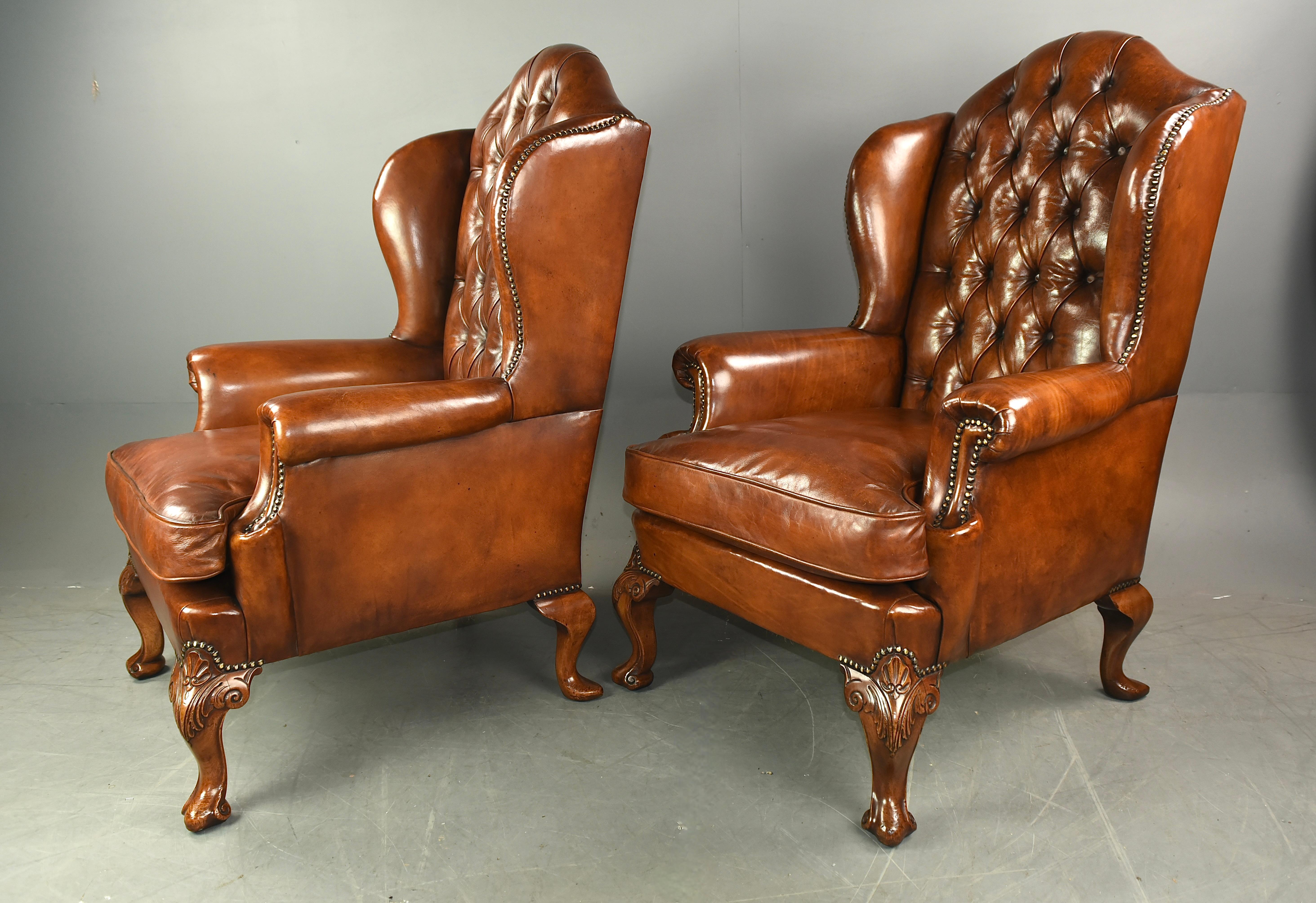 These large Antique leather wing chairs circa 1900 feature a rich ,patinated hand dyed leather upholstery that been newly upholstered  with intricate brass studding ,The high curved backs give the chairs a sense of elegance .standing on fine carved