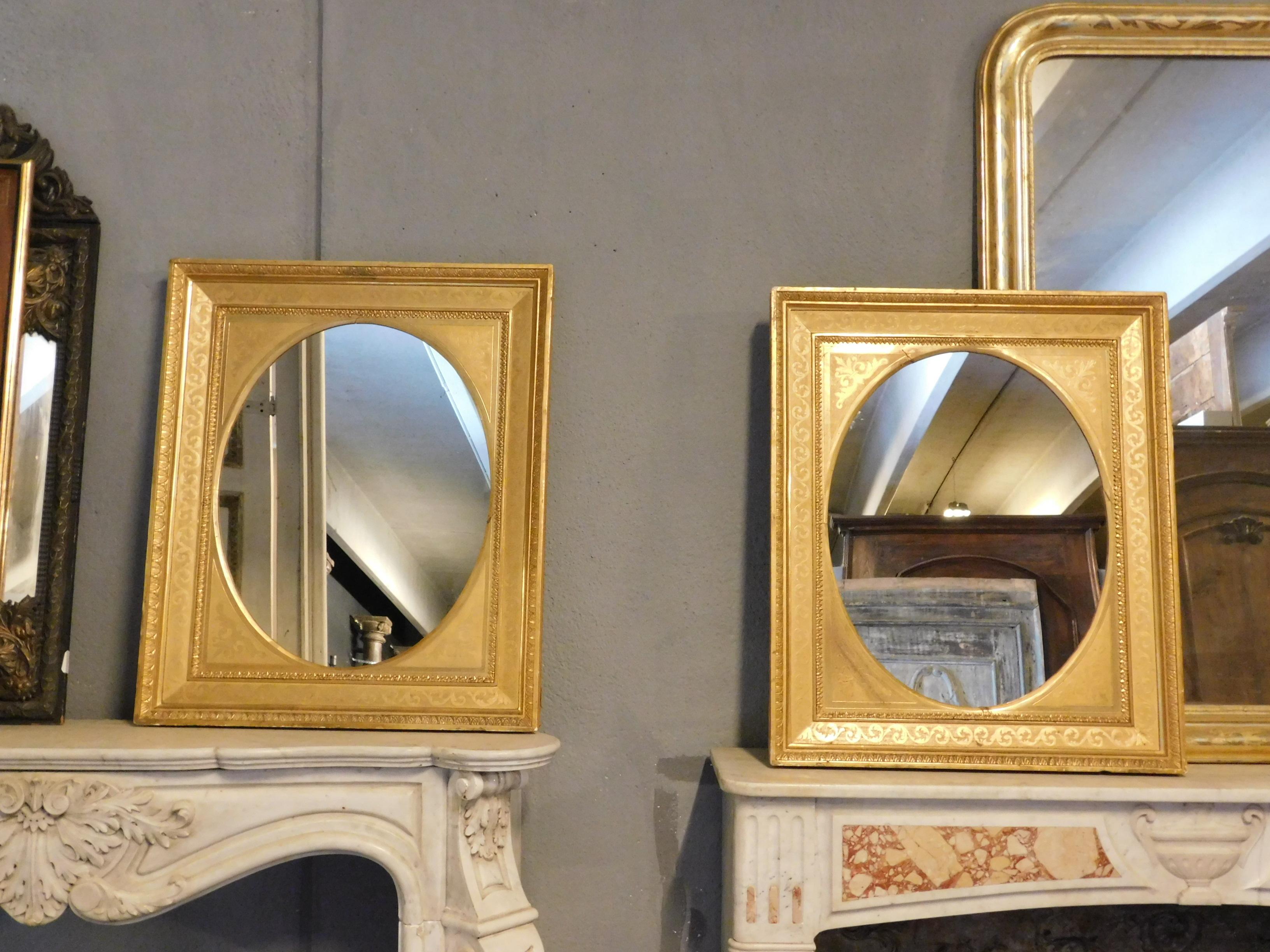Antique pair of golden rectangular mirrors with oval internal mirror, decorations and engravings on the gilded wooden frame, built in the second half of the 19th century in Italy, beautiful in pairs, suitable for any environment given the size,