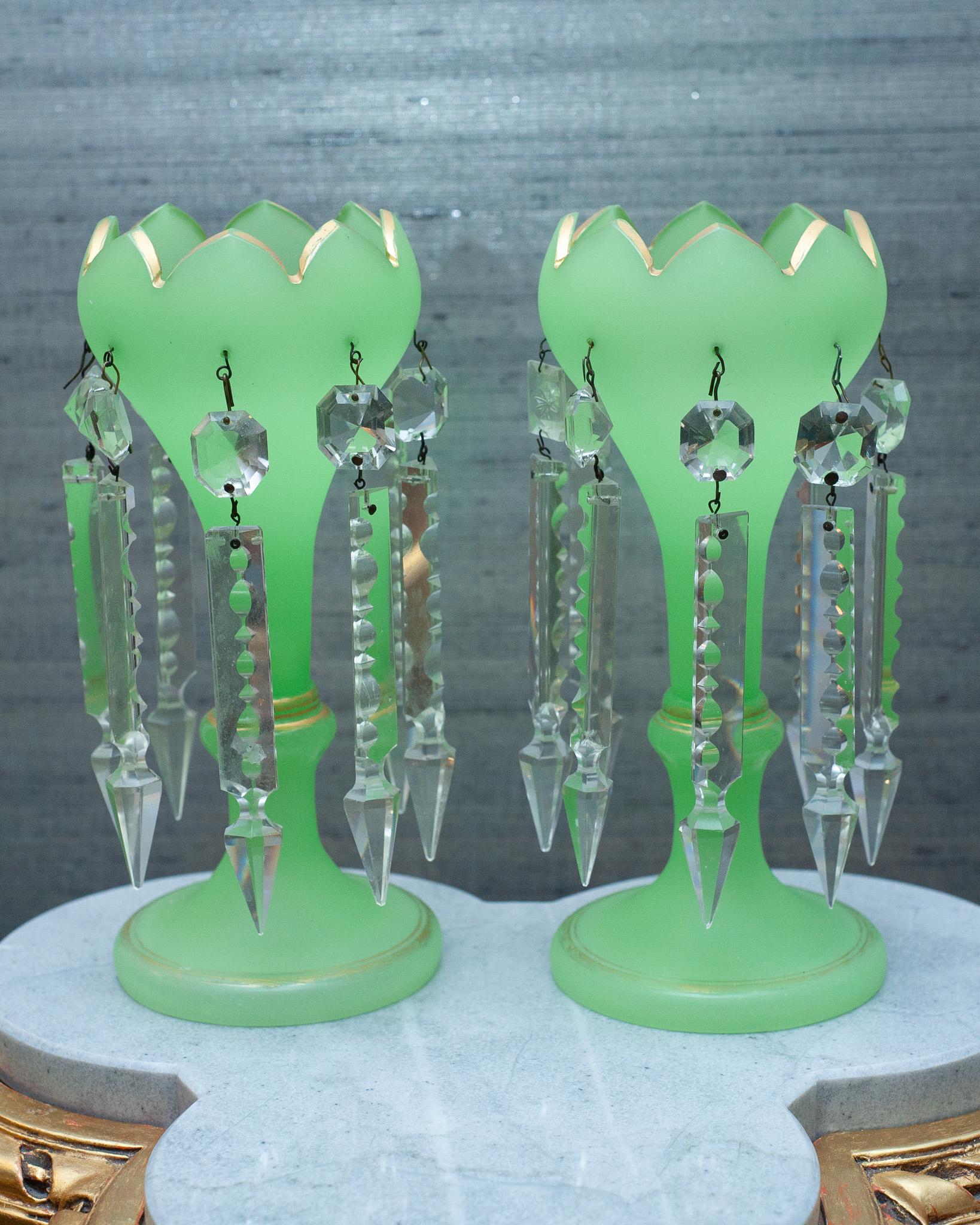 A stunning pair of Antique French opaline glass mantle lusters, in green opaline glass with gilding and scalloped edge, and cut crystal prisms. Each luster has 8 hanging prisms.
