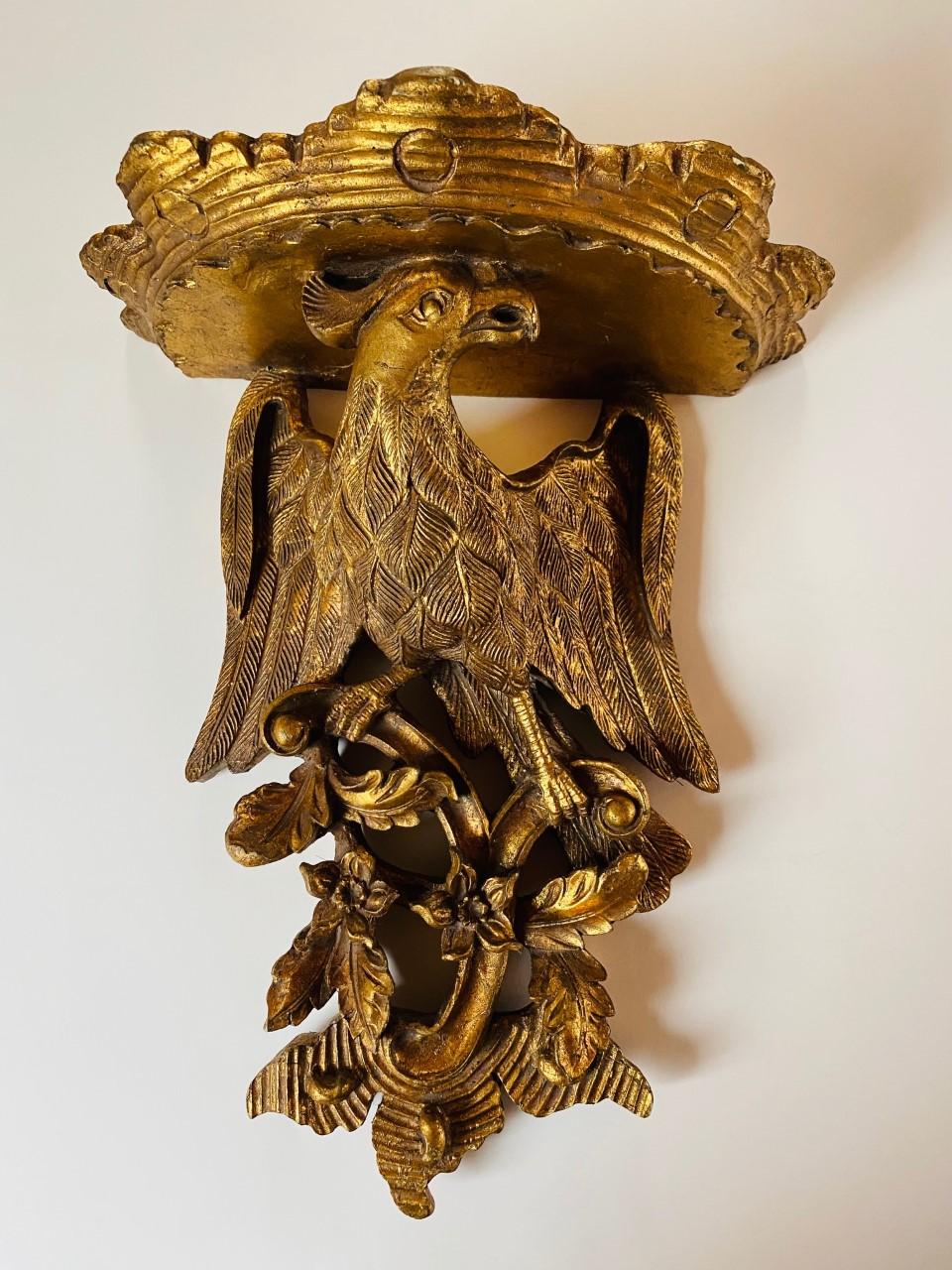 Vintage pair of eagle composite wood carved wall shelf sconces in a gilt finish. Each sconce is finely sculpted and the pair will complement and elevate any décor or use. The pair will enhance your Art Deco or Hollywood Regency styles. An ideal