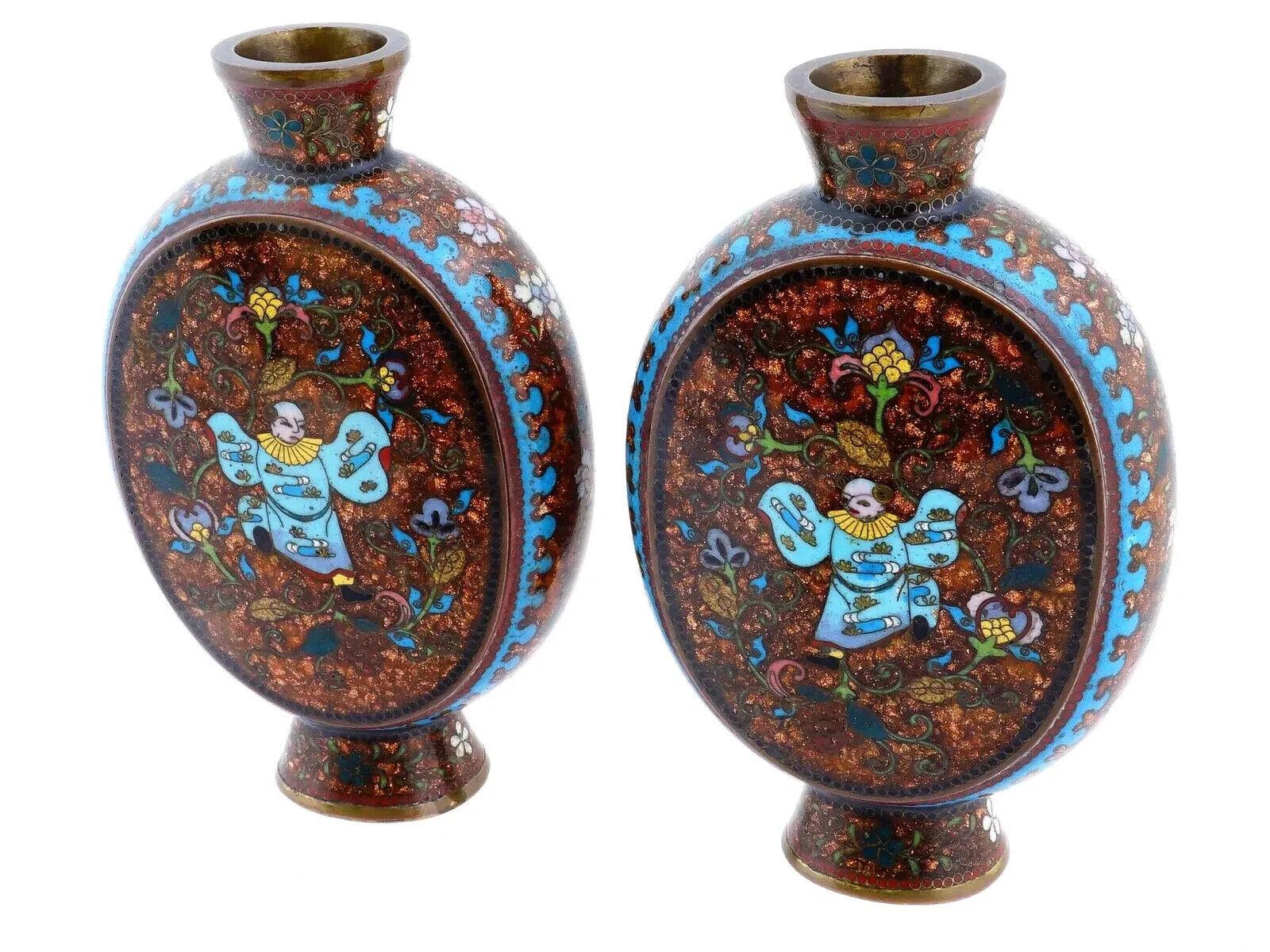 Paire de vases japonais à pied en forme de flasque de lune en émail sur cuivre. L'extérieur des vases est orné d'un motif polychrome représentant une danseuse entourée de motifs floraux, de feuillages et de rinceaux réalisés selon la technique du