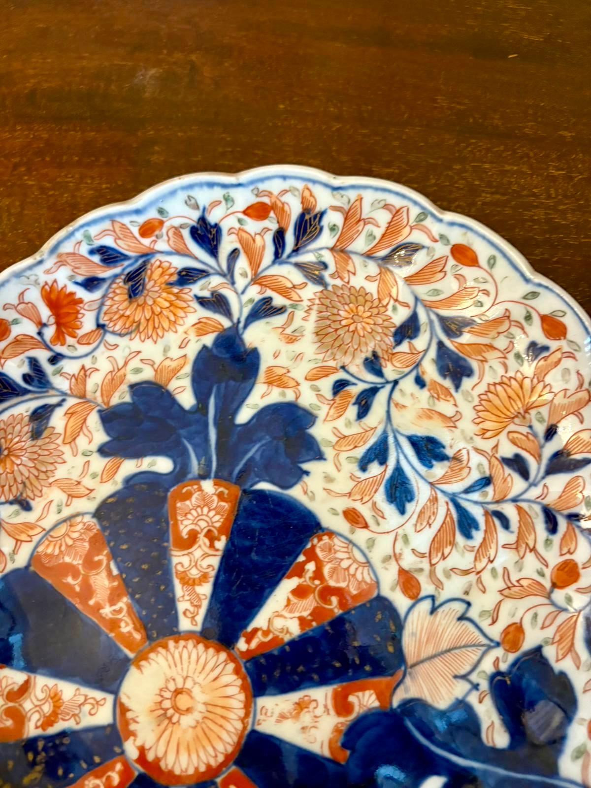 Ein bezauberndes Paar japanischer Imari-Teller mit Wellenschliff, dekoriert in der traditionellen Farbpalette von Kobaltblau (Unterglasur) und Eisenrot (Überglasur) mit vergoldeten Highlights. Jeder Teller zeigt ein kühnes zentrales Rondell mit