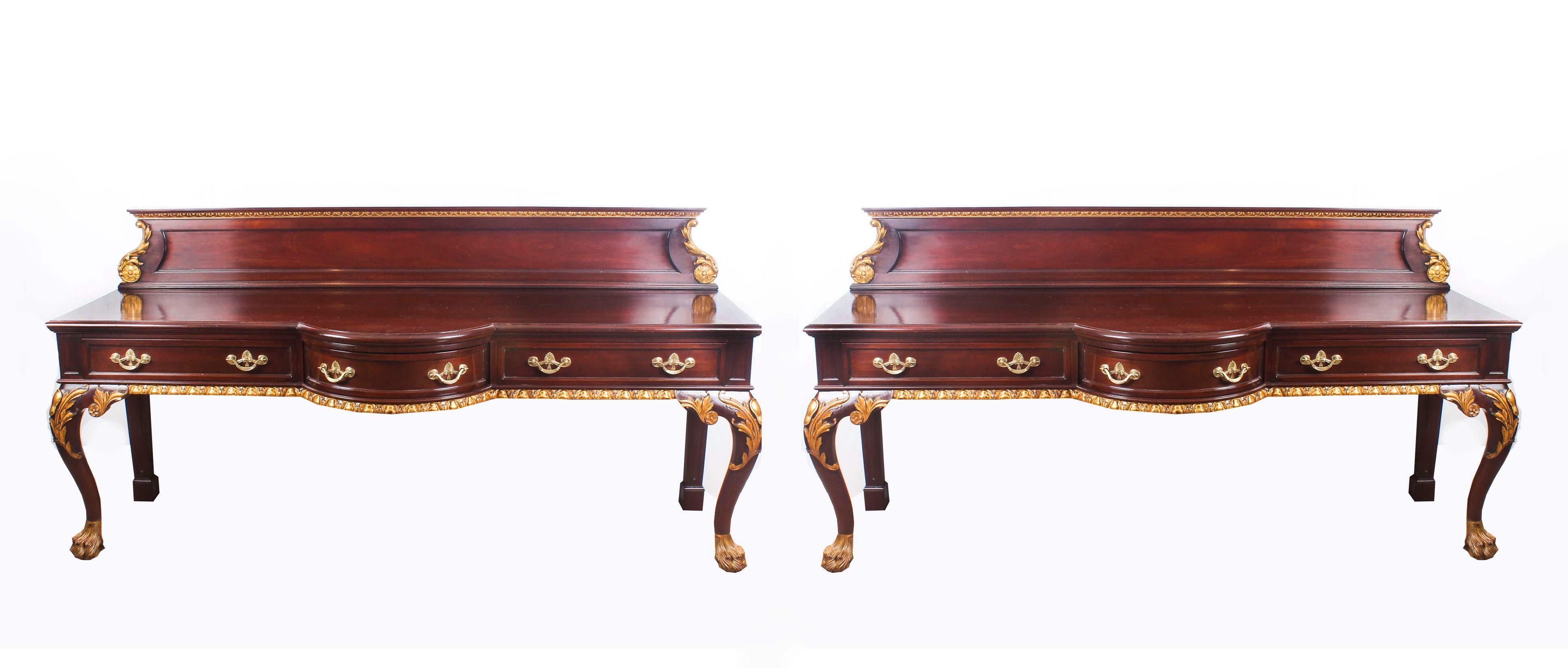 This is a fine monumental pair of antique mahogany and parcel gilt serving tables in the George II style, dating from the 19th century.

The backs are decorated with egg and dart moulding and acanthus scrolls. Each central bowfront drawer is flanked