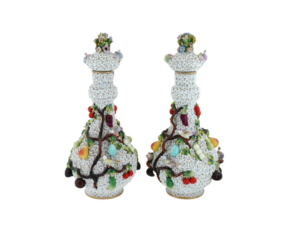 A pair of antique German Meissen manner Schneeballen Snowball lidded bottle vases. Each vase has a gilt vermiculite neck, applied white florals, and applied branches with fruits and birds, on the bodies. The lids are decorated with sculptural
