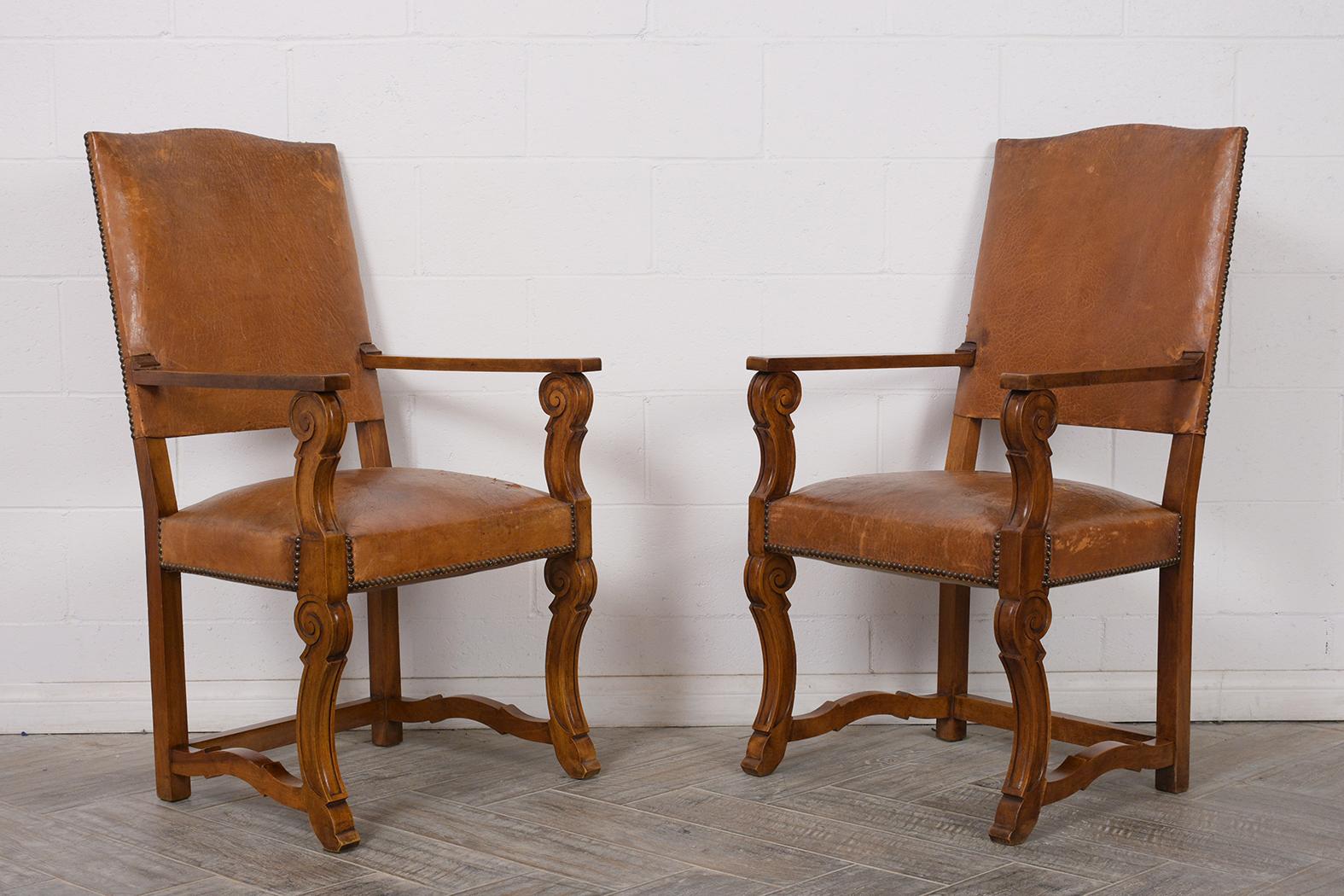 Pair of 1880s armchairs, solid walnut wood frames, with original dark walnut finish. They have high backs, with carved front arms, and stretched carved legs. Chairs are covered in original dark brown/walnut color leather, with nail-head trims.