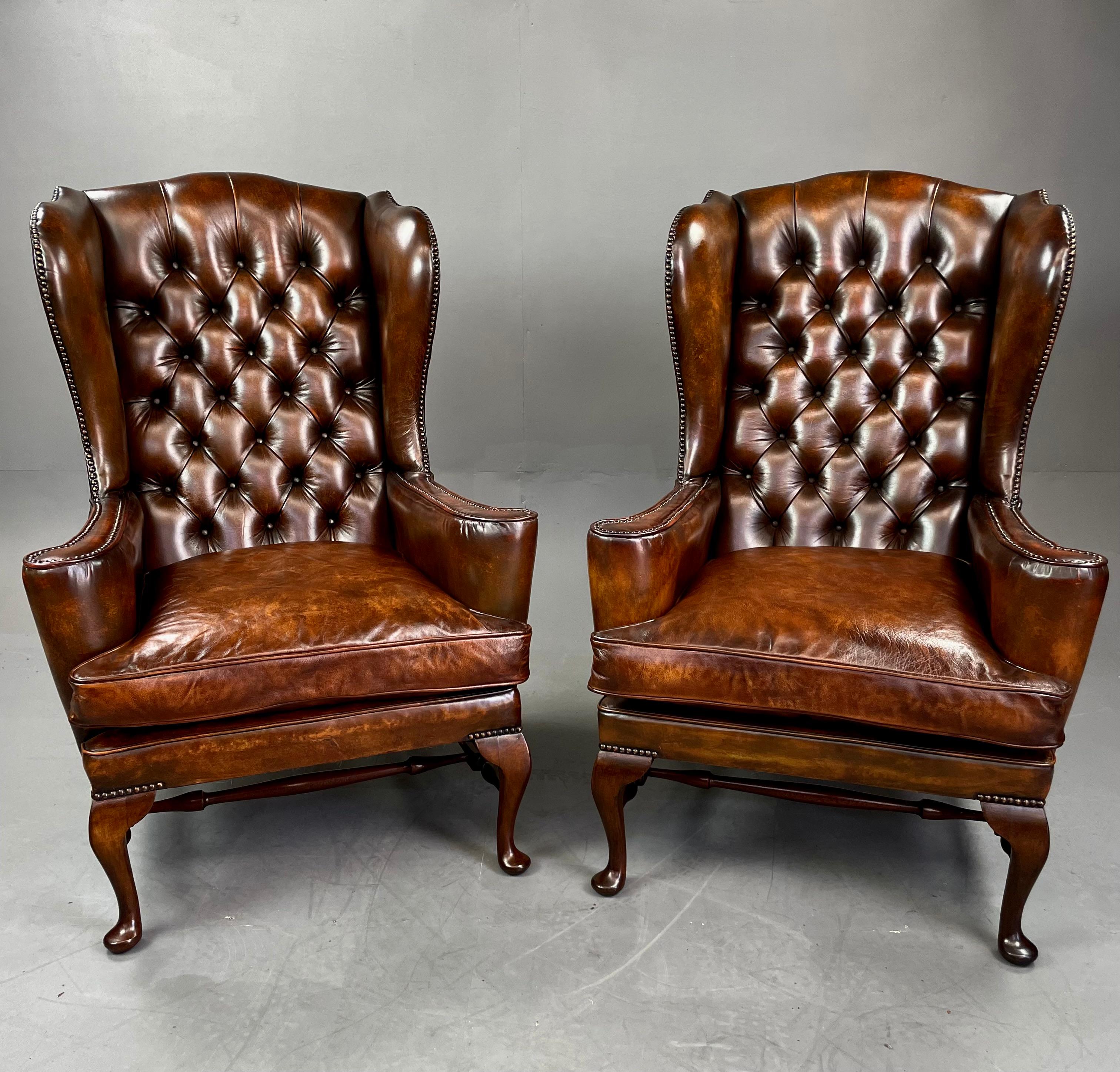 A fine pair of English Antique leather wing chairs hand dyed and finished to give a unique finish. The chairs are all original leather with deep buttoned backs and antique brass stud work accept replacement cushions which have been deep stuffed for