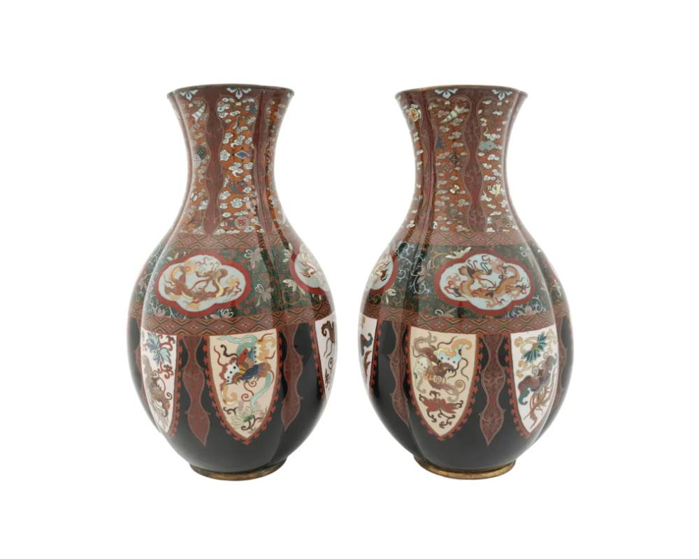 A pair of antique Japanese Meiji era enamel metal vases. The lobed shaped vases are enameled with polychrome medallion images of dragons and butterflies, floral, foliage, and geometrical motifs made in the Cloisonne technique. The ground is inlaid