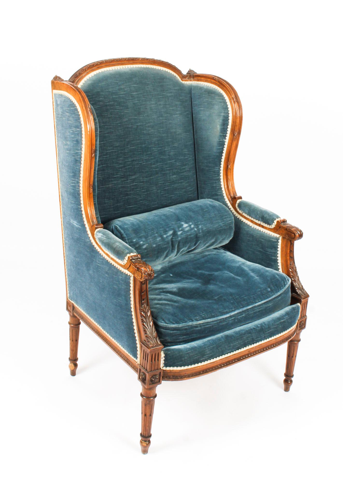 This is an elegant antique pair of mahogany Louis revival wingback armchairs, circa 1880 in date. 

The mahogany is beautiful in color and features skilfully carved acanthus leaf decoration. They are upholstered in sapphire blue velvet with