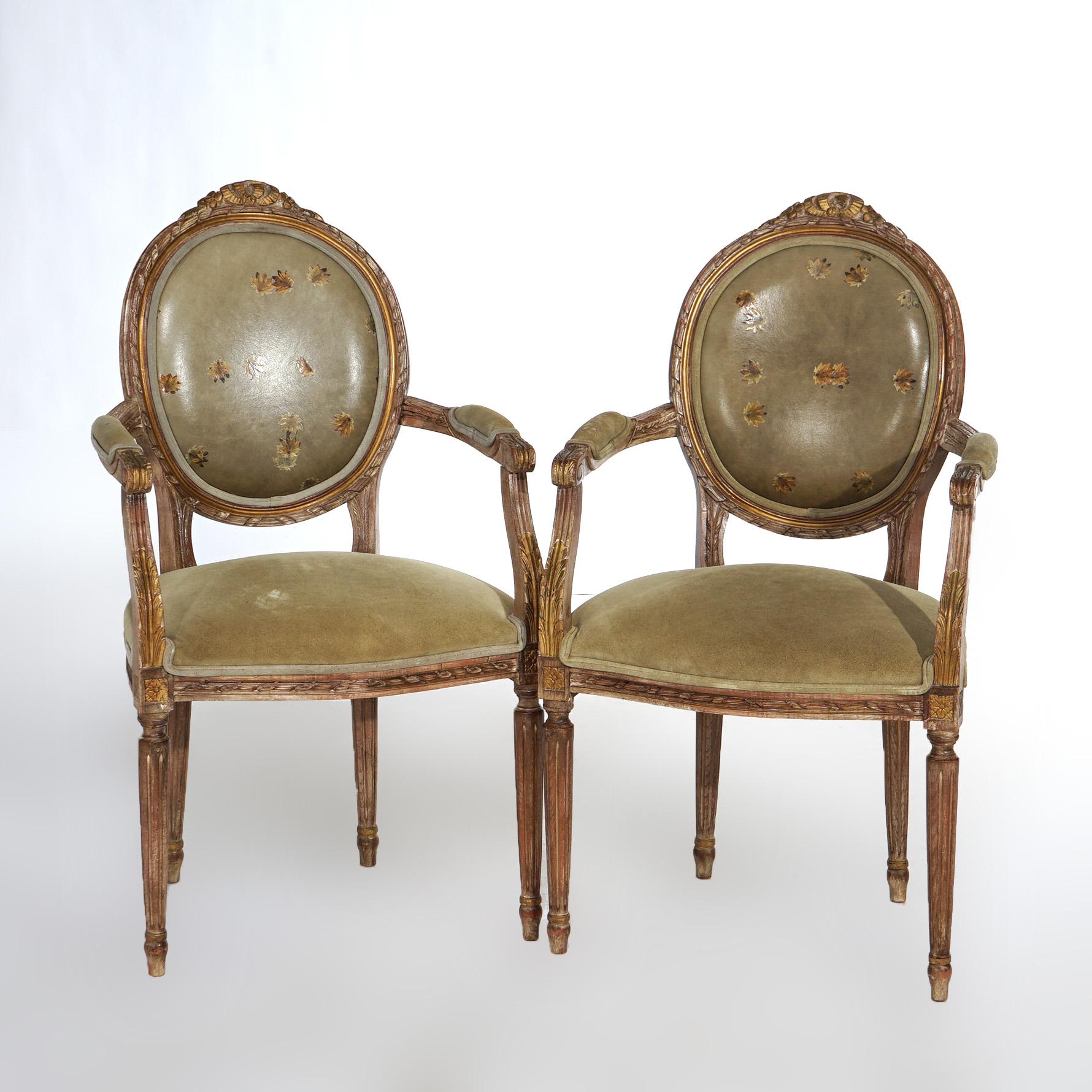 An antique pair of French Louis XVI style armchairs offer giltwood frames with carved foliate elements housing leather backs and seats with hand painted flower design, 20th century

Measures - 39