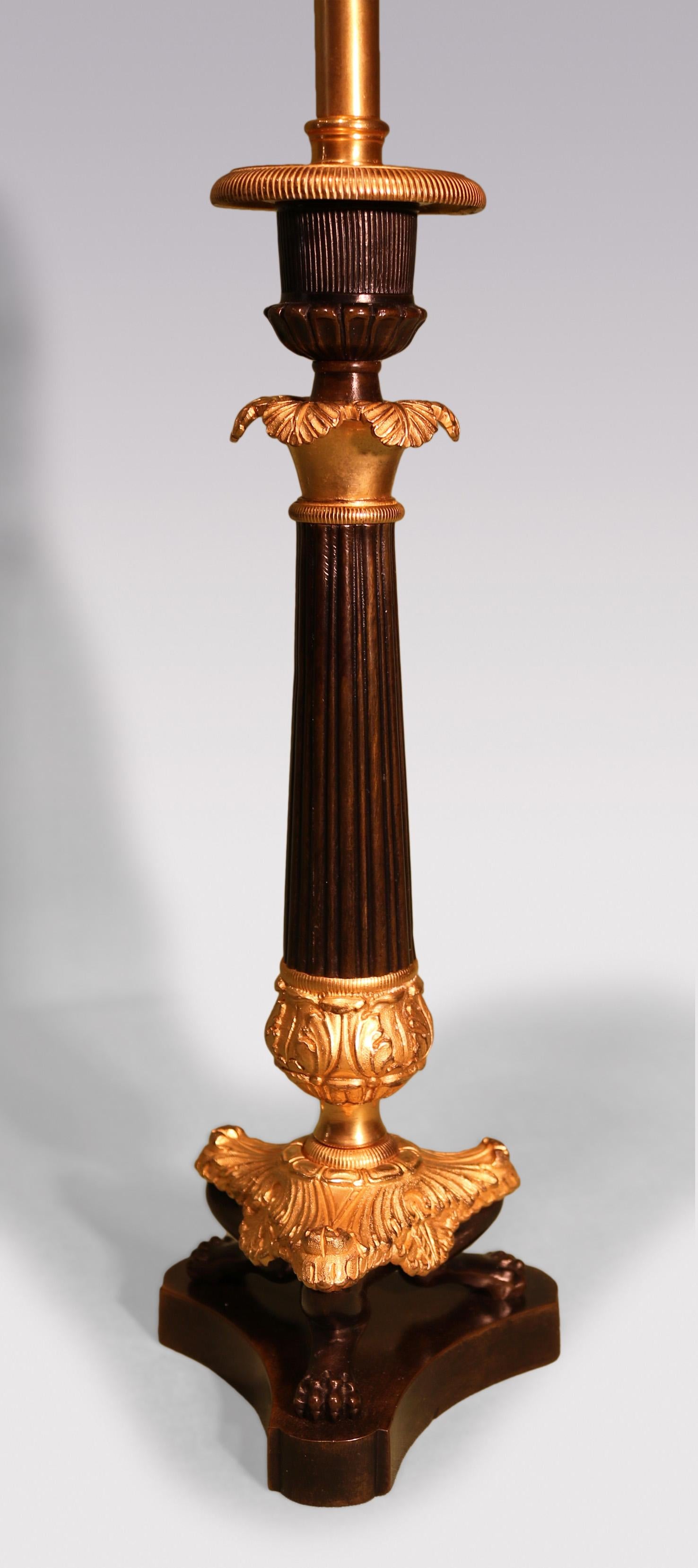 A Pair of Mid-19th Century bronze & ormolu Candlesticks having reeded sconces above leaf scrolled reeded tapering stems with leaf scroll & lion’s paw triform bases.