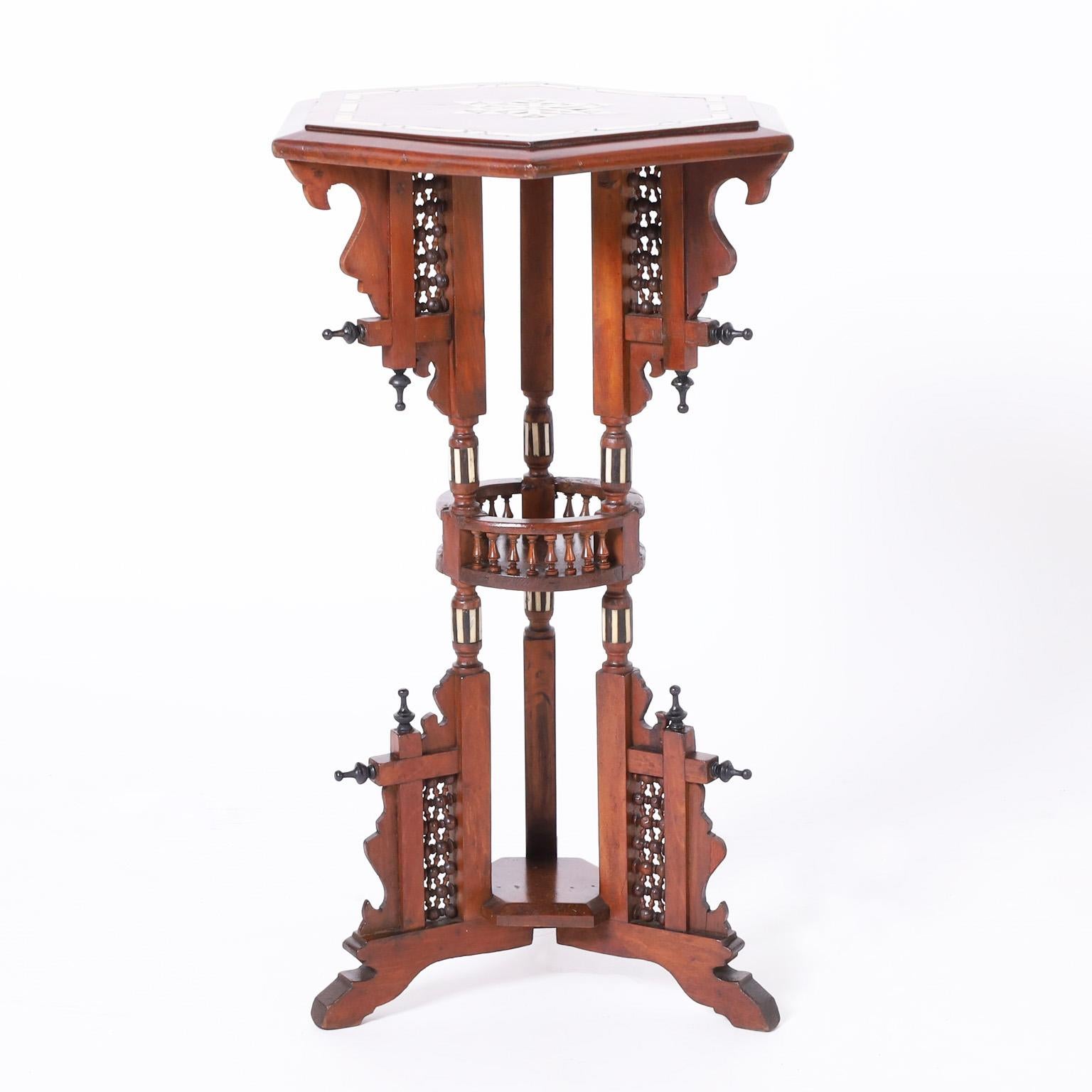 Standout pair of Moroccan stands crafted in mahogany having hexagon form tops with inlaid bone, mother of pearl and ebony in geometric designs on aesthetics movement bases with stick and ball panels, finials and a gallery on three bracket feet.