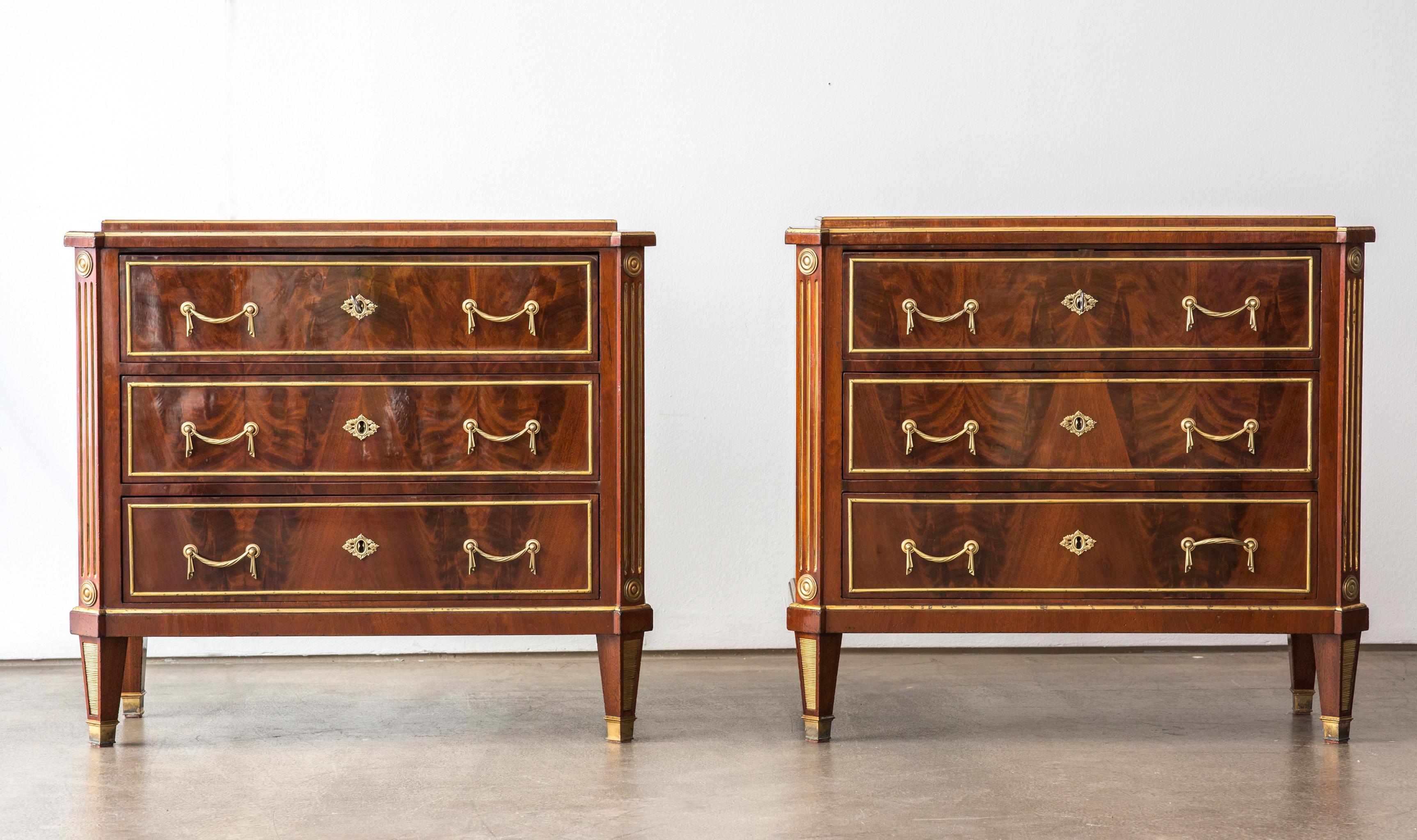An original antique pair of neoclassical chests of drawers from the early 19th century from Russia.
The commodes are made from Mahogany veneer and decorated with brass lasts and fittings.

Each chest has three drawers, which are veneered with