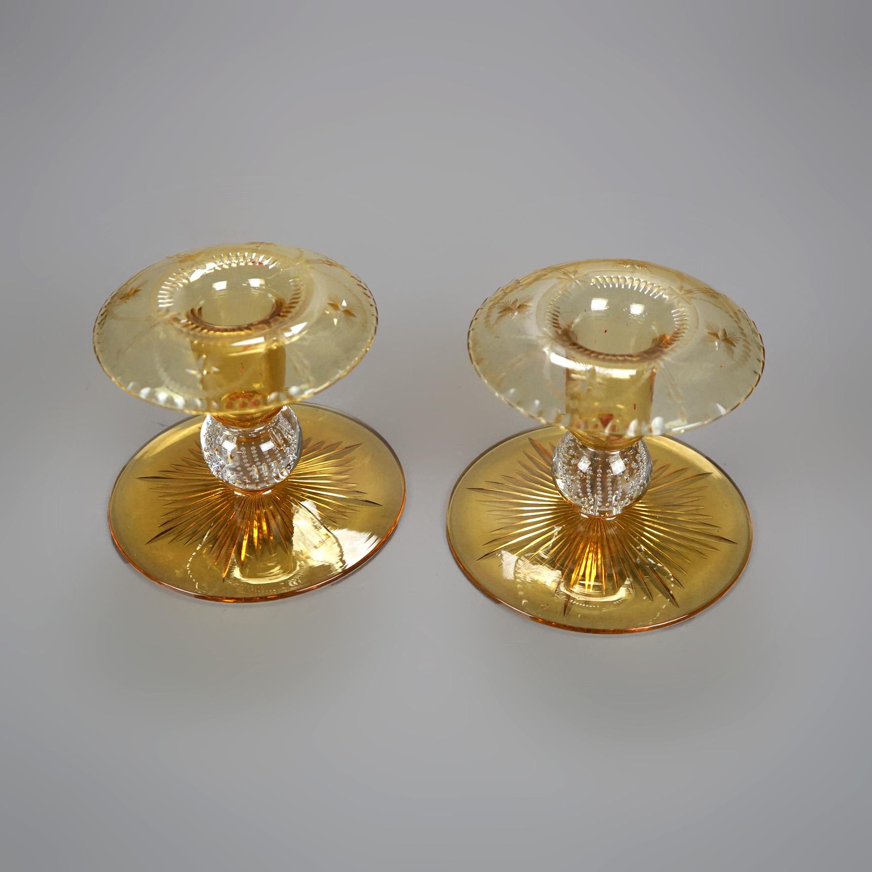 An antique pair of candlesticks by Pairpoint offer amber art glass construction in squat balustrade form and having cut design including sunburst on base and colorless bubble glass in stem, unsigned, c1920

Measures- 4.25''H x 5''W x