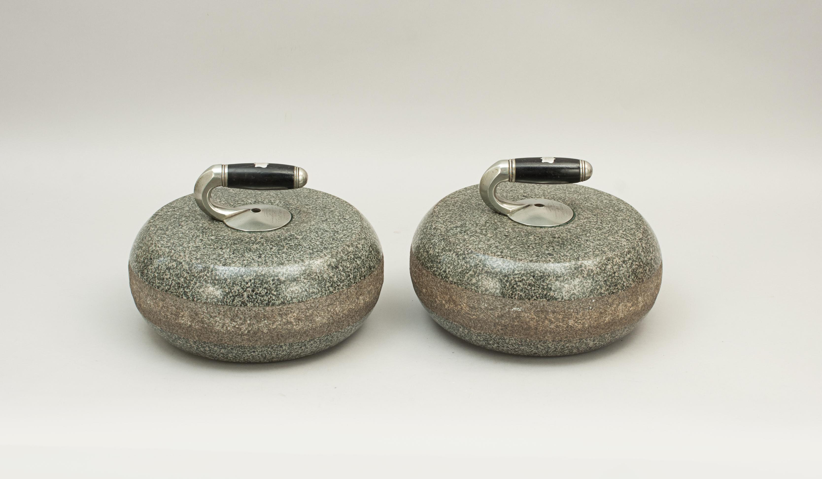 Two presentation granite curling stones.
A fine pair of traditional grey granite curling stones with removable handles. The stone is most probably made from granite from Ailsa Craig by Turnberry, Scotland. The stones have dips in the top to locate
