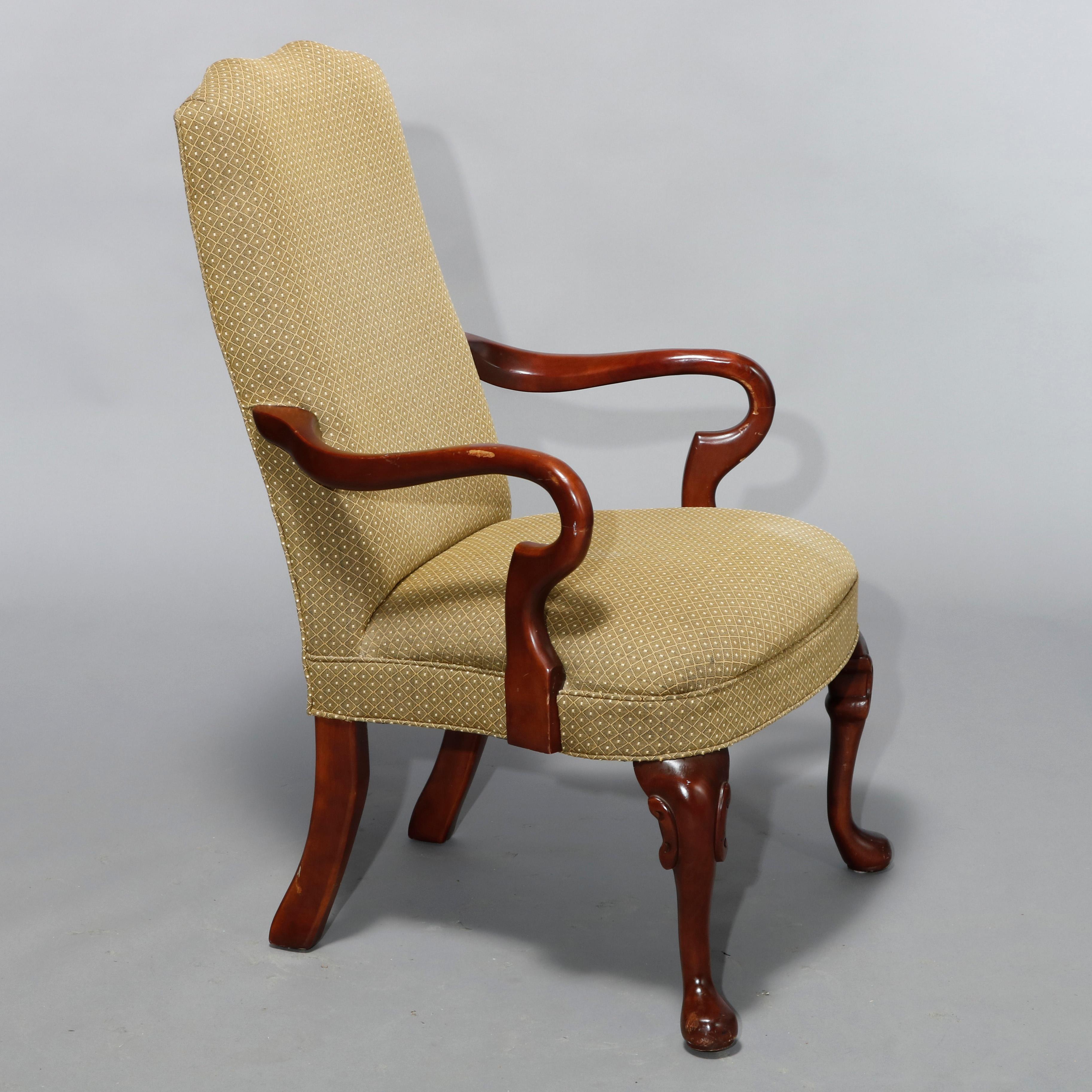 An antique pair of Queen Anne style fireside armchairs offer shaped and upholstered backs and seats on mahogany frames with scroll arms and cabriole legs having carved knees and pad feet, 20th century

Measures: 41.75