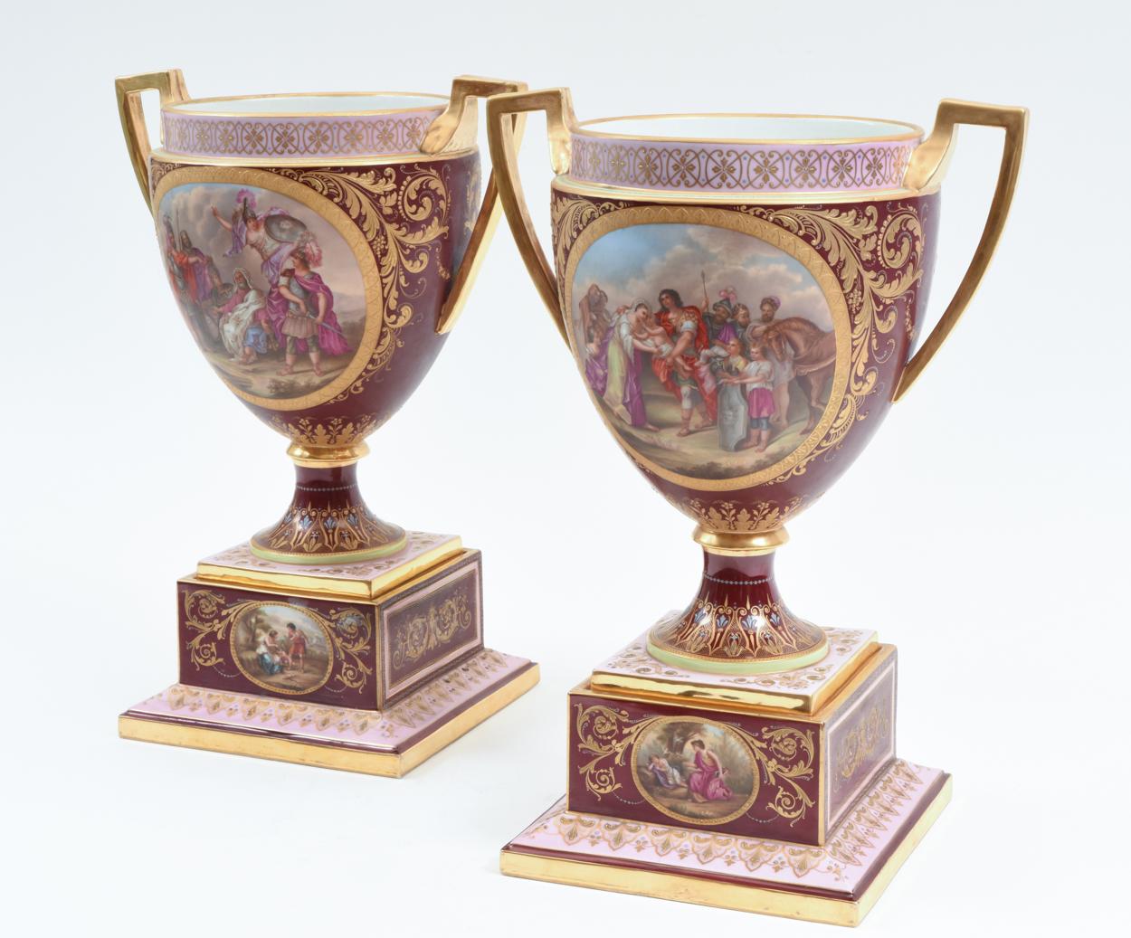 Antique hand painted pair of Royal Vienna Porcelain uncovered decorative piece / urn. Each piece have two gilt side handles with hand painted panels design details. Each one is set on squared hand painted design details holding base. Each piece /