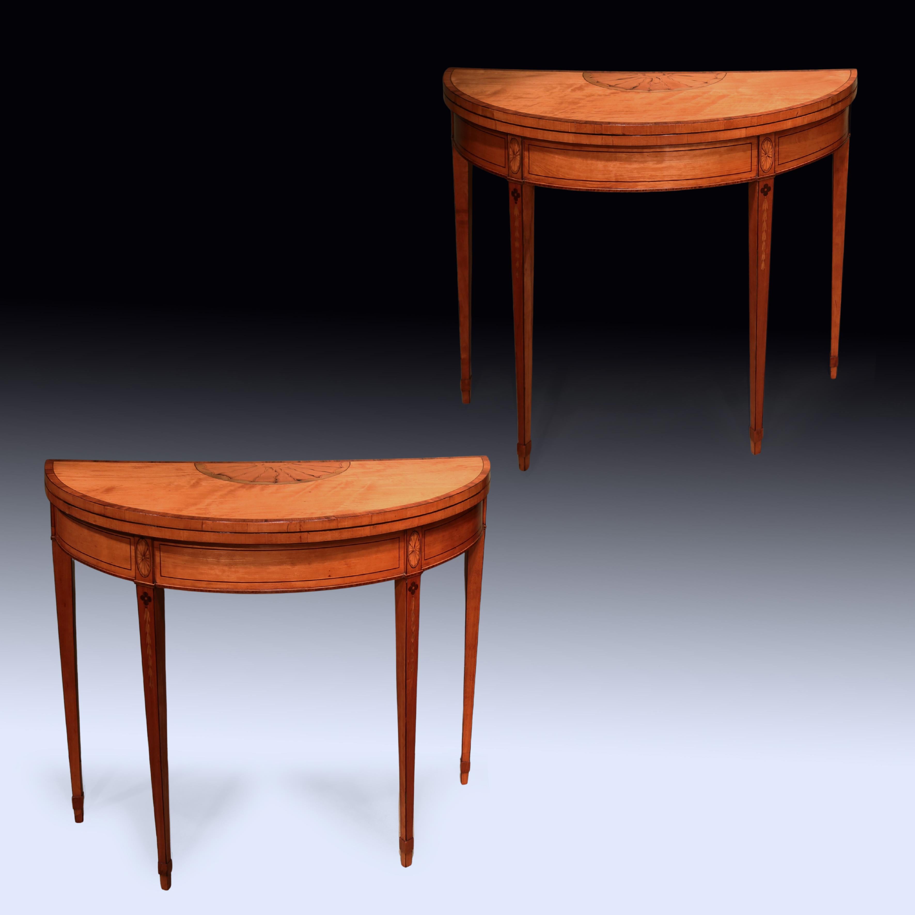 A fine pair of late 18th Century Sheraton period satinwood Demilune Card Tables, ebony strung throughout, having kingwood crossbanded tops with central boxwood oval sunburst panels, supported on oval panelled & husk inlaid square tapering legs with