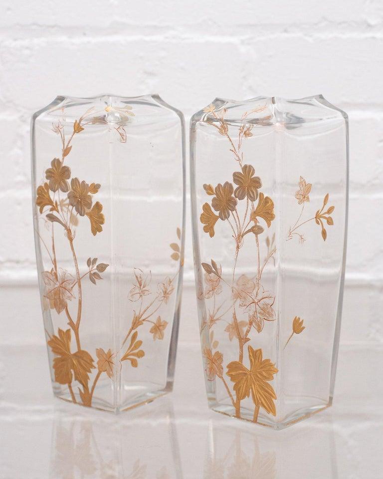 This beautiful pair of antique Baccarat vases, circa 1940, is dedicated gilded with branches and leaves, wrapping around three sides of the crystal body. Baccarat signature etched into crystal on the bottom of each vase.