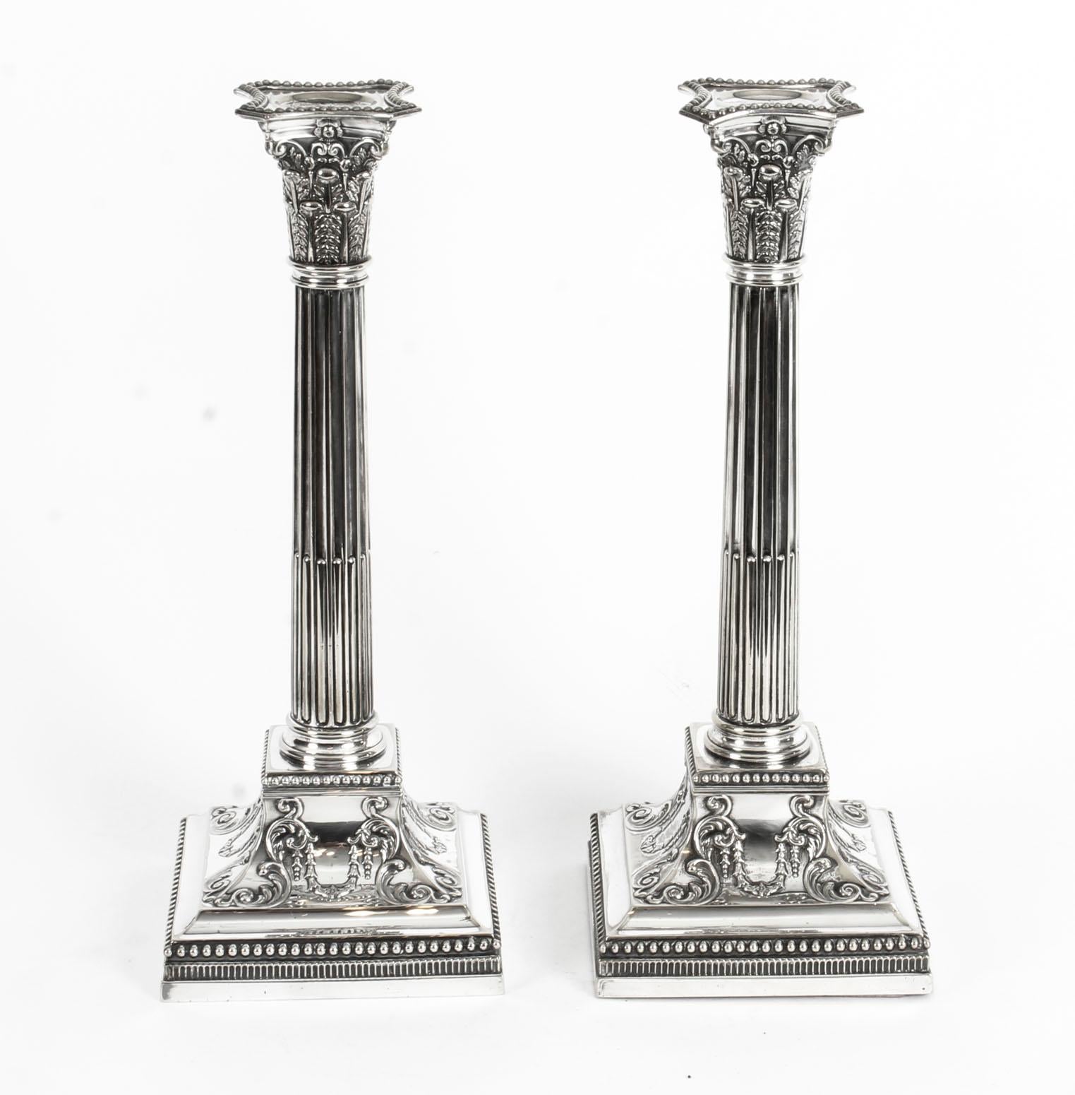 This is an exquisite pair of antique English silver plated candlesticks in neoclassical Corinthian column style and bearing the makers marks, inside the sconces, of the renowned silveresmith, James Dixon & Sons, Sheffield, circa 1870 in