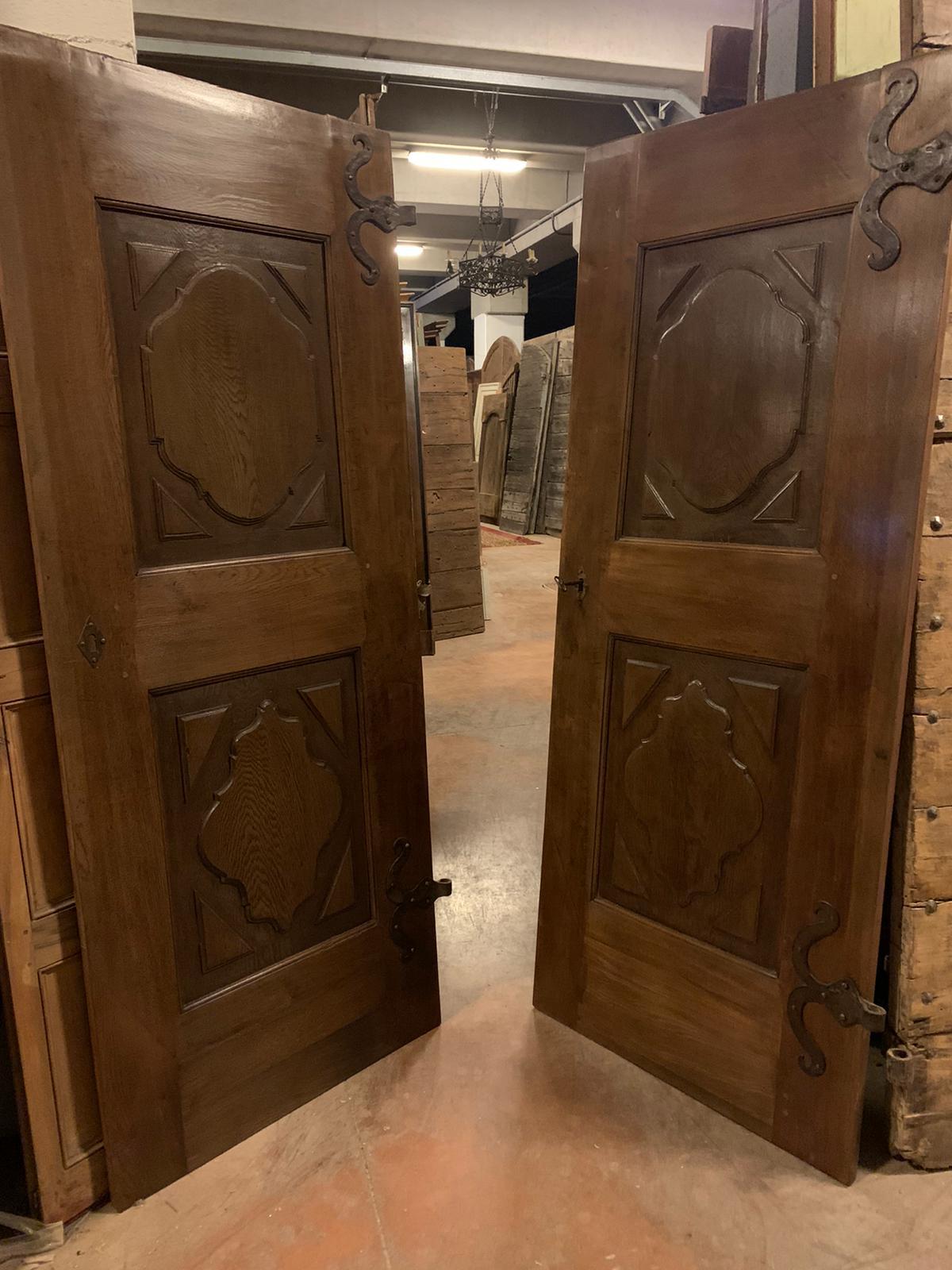 Antique set of pair of single oak doors, panels carved with Baroque motif, from Piedmont (Italy), built and sculpted entirely by hand in the 18th century, complete with beautiful irons for wall mounting, butterfly irons and lock with original key.