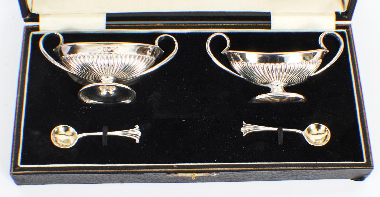 This is a charming cased pair of antique Victorian sterling silver salt cellars each in the form of a two handled vase with handles, and a pair of Onslow pattern salt spoons, bearing makers mark of Fenton Bros, and hallmarks for Sheffield, 1881.
