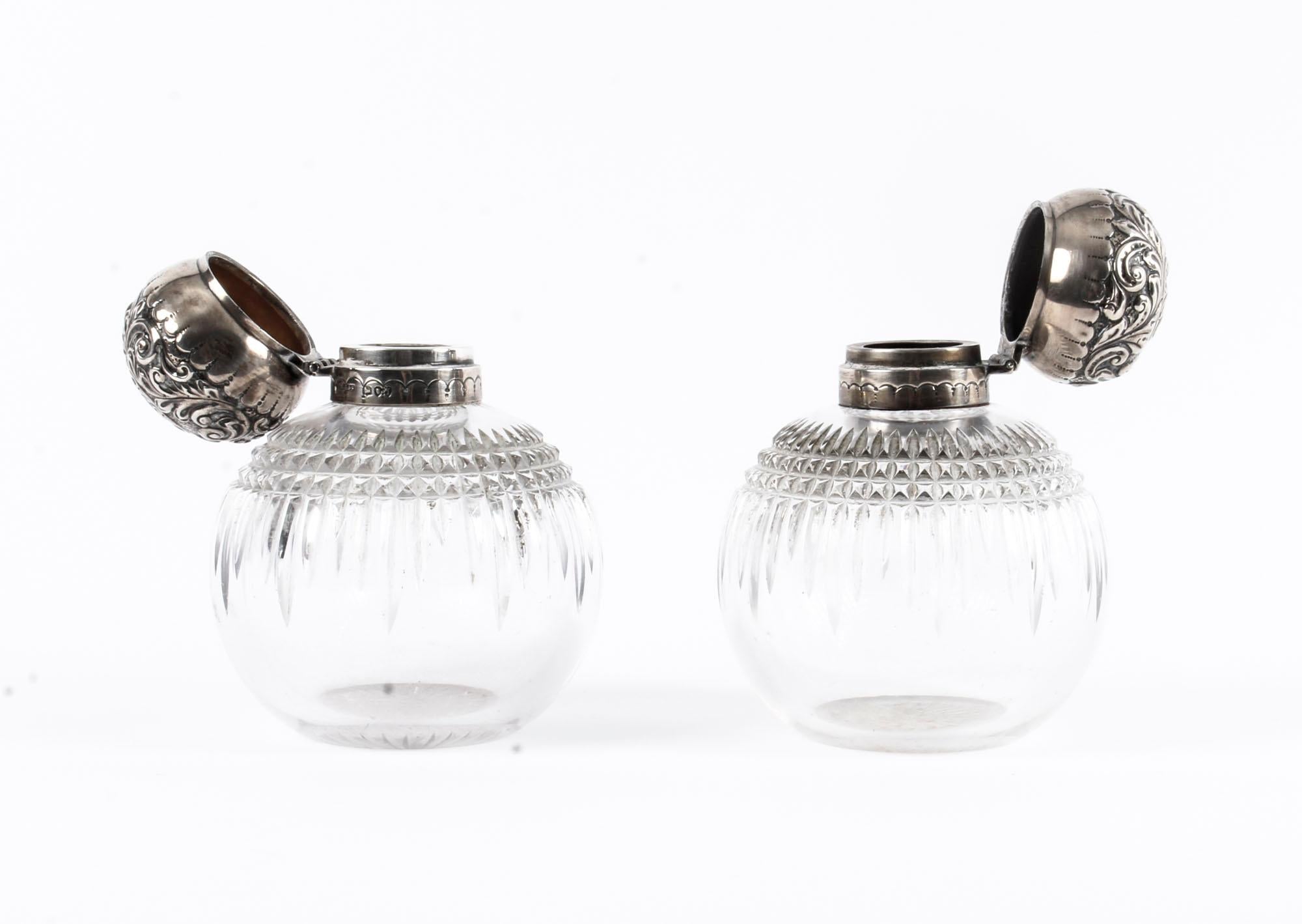 This is an exquisitely sophisticated and rare pair of Antique Victorian sterling silver top and clear cut crystal scent bottles, by the renowned silversmiths John Grinsell & Sons of London, 1894 in date.

Each bottle features a distinctive