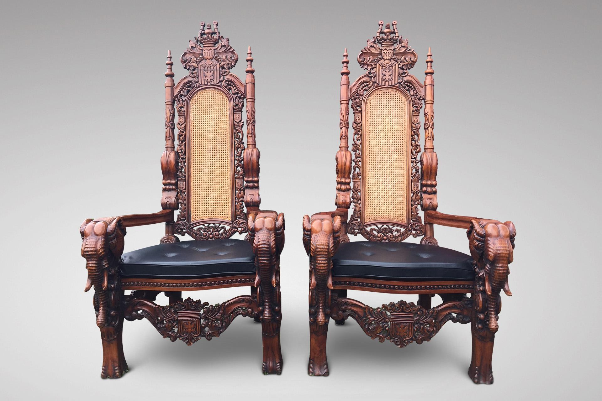 An antique pair of impressive carved walnut elephant high backed Throne Armchairs, cane back and seat rest, with a fitted black leather loose cushion. Stunning quality.

The dimensions are:
Height: 178cm (70.1in)
Width: 94cm (37.0in)
Depth: 75cm