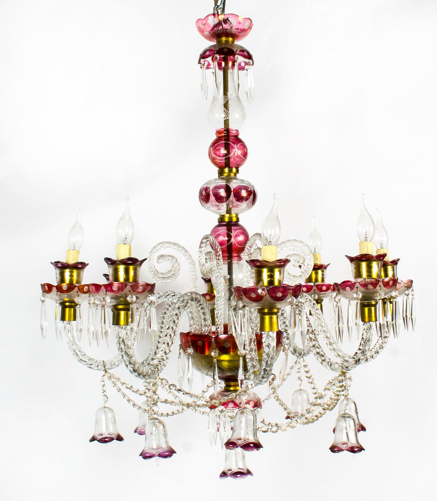 This is a beautiful pair of antique Venetian crystal chandeliers with eight lights, circa 1900 in date.

The delicate and elaborate hand blown clear crystal with cranberry red highlights. The chandeliers feature eight scrolled sconces each arm