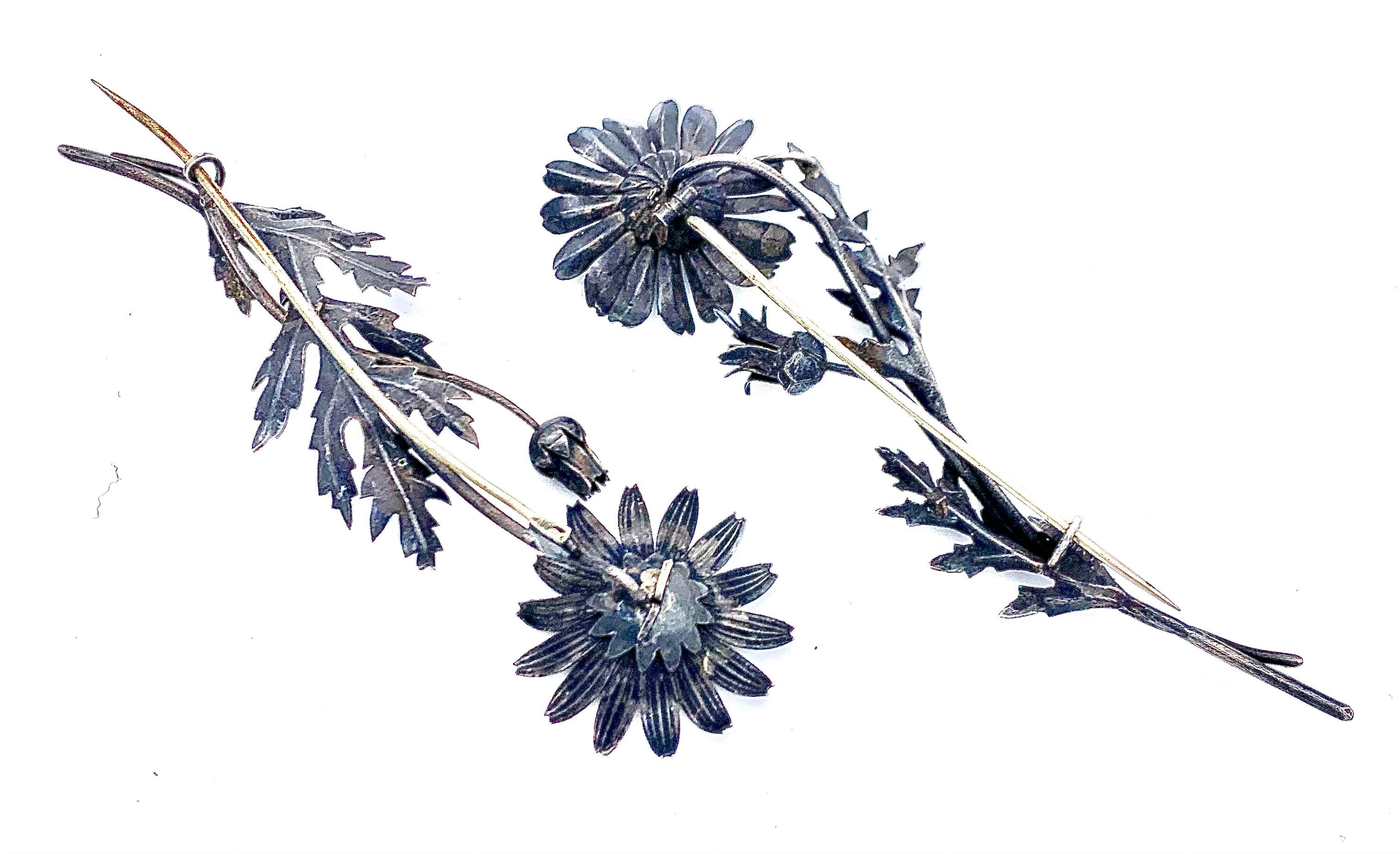 Rare pair of finely modelled naturalistic flower brooches. The flowers are  hand crafted out of silver
around 1850.
The flower with the closed flower bud is slightly shorter, it meassures 11.5 cm, the width is 4 cm. It is heavier than the other
