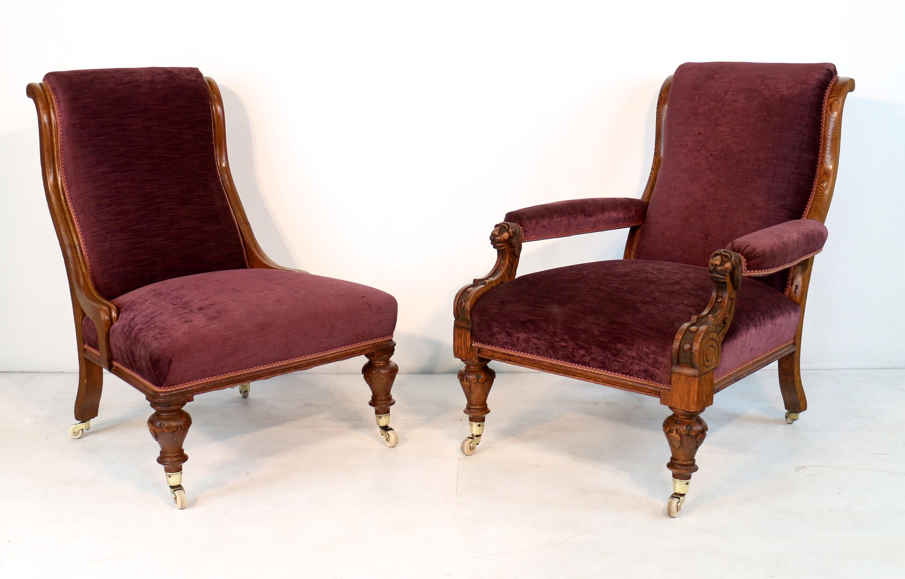 A superb pair of Victorian his and hers library chairs, circa 1870, the gentleman’s armchair with carved lion head terminals to the padded armrests, each with shaped back and deep seat and recently reupholstered in aubergine purple velvet chenille