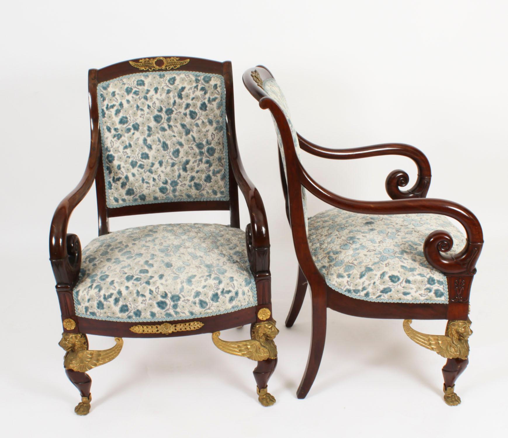 This is a fantastic and highly decorative antique pair of French ormolu mounted mahogany Empire fauteuil armchairs,  circa 1870 in date.
They feature scrolled square padded backs mounted with laurel and anthemion ormolu mounts above stuff-over seats