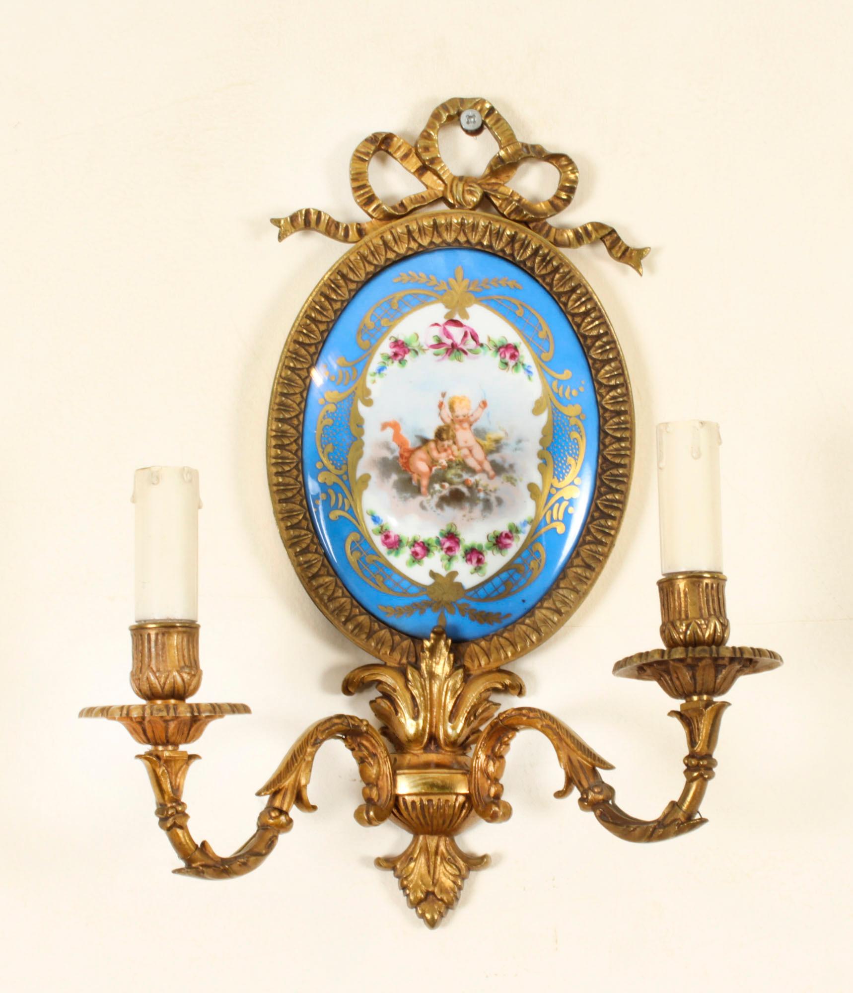 This is a stunning Antique pair of Sevres porcelain and ormolu wall lights,  Circa 1870 in date.

They feature hand painted oval plaques depicting cherubs in clouds surrounded by floral drapes with gilt high-lights and ormolu leaf cast mounts and