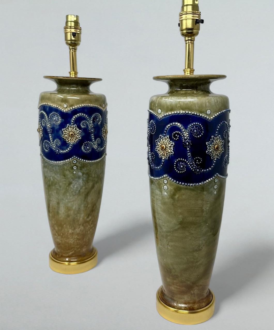 A Very Stylish Identical Pair of English Ormolu Mounted Royal Doulton Lambeth Moulded Salt-Glaze Stoneware Pottery tall slender mantle Vases by Ceramic Artist Minnie Webb, now converted to a pair of electric Table Lamps. Circa 1920s. 

Each of