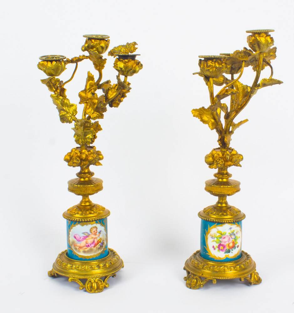 This is a delightful antique pair of 19th century French Sèvres porcelain mounted ormolu candelabra.
 
The cylinder-shaped Sèvres porcelain columns feature hand painted panels of summer flowers and cherubs on a bleu celeste ground with gilt