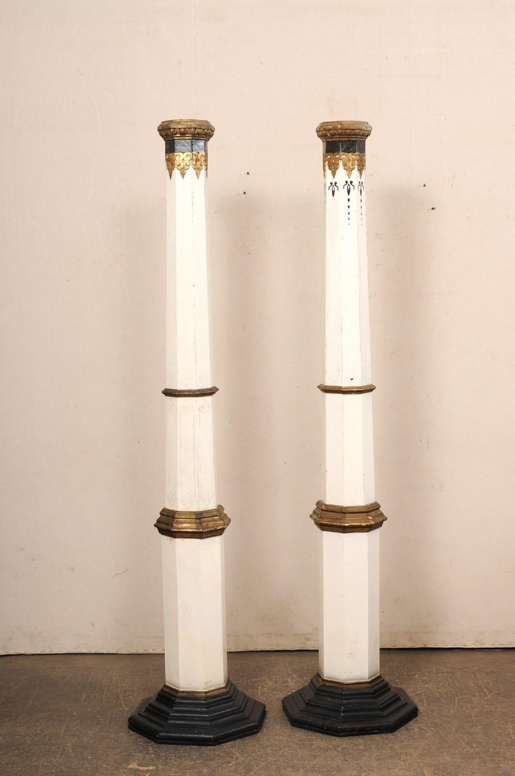 A Spanish pair of tapering, painted wood columns from the early 20th century. This tall pair of antique pillars from Spain, each with a hand-painted, decorative finish, have octagonal-shaped and tapering bodies, with egg and dart trim about their