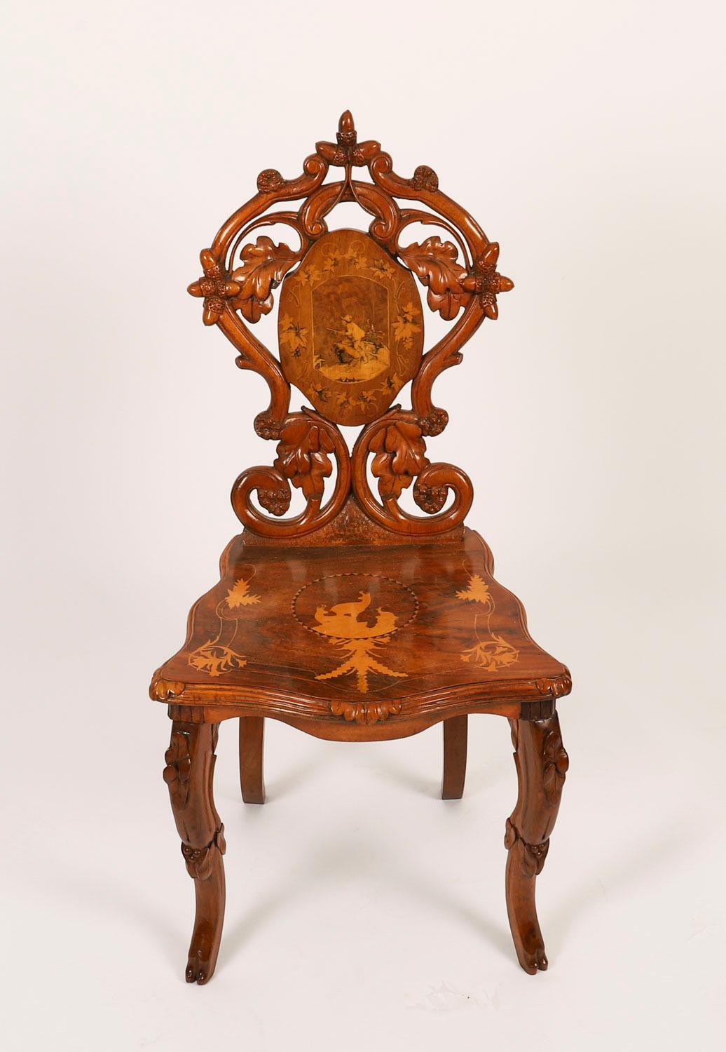This is a superb pair of antique 19th Century Swiss carved walnut and marquetry inlaid hall chairs.

They have striking inlaid Alpine hunting scenes to the backs, the figures in Bavarian clothing, the seats are decorated with inlaid Goat and Chamois