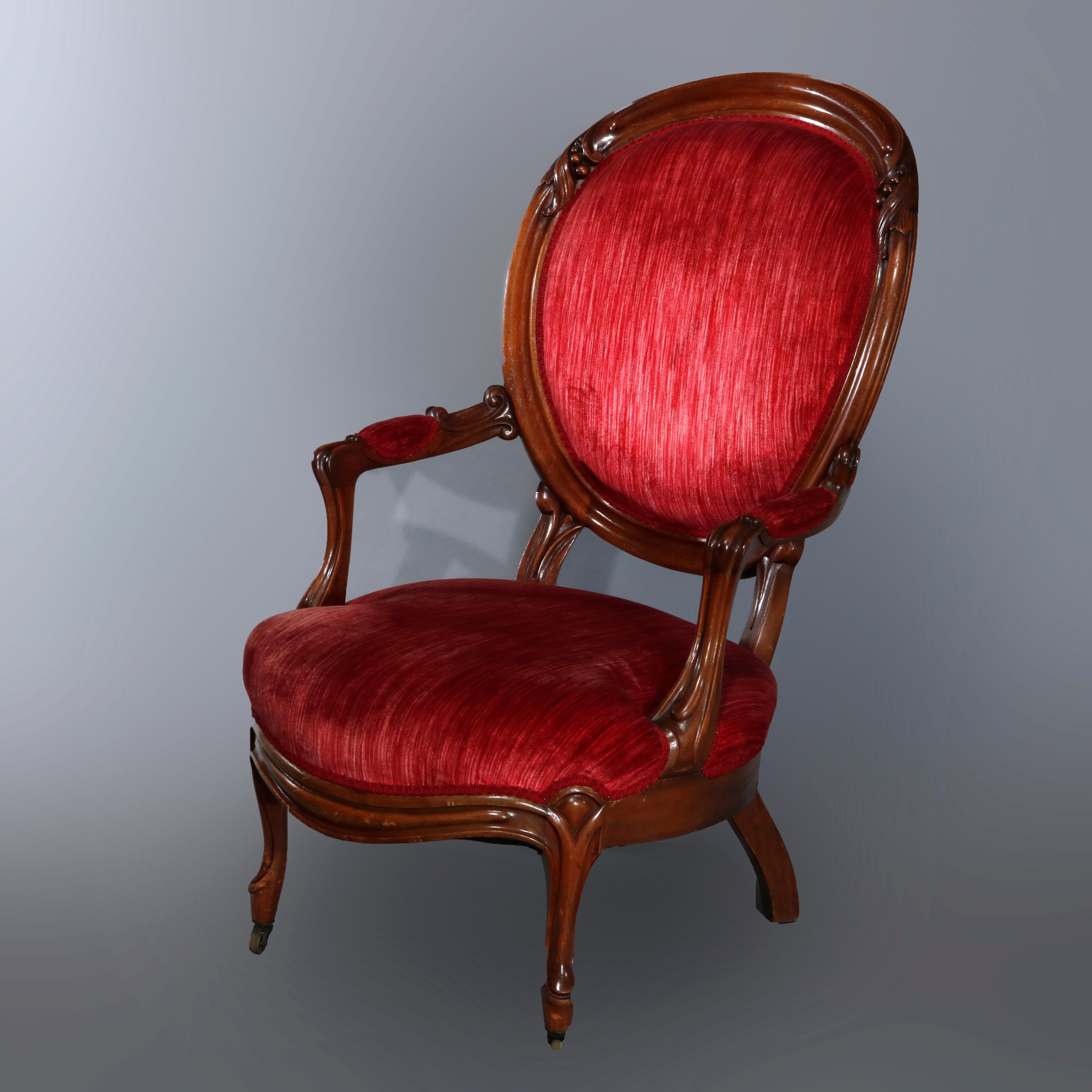 An antique pair of Victorian parlor armchairs offer carved walnut frames with foliate elements, upholstered ballon backs and covered arms surmounting upholstered seats raised on cabriole legs, circa 1890.

Measures: 39.5