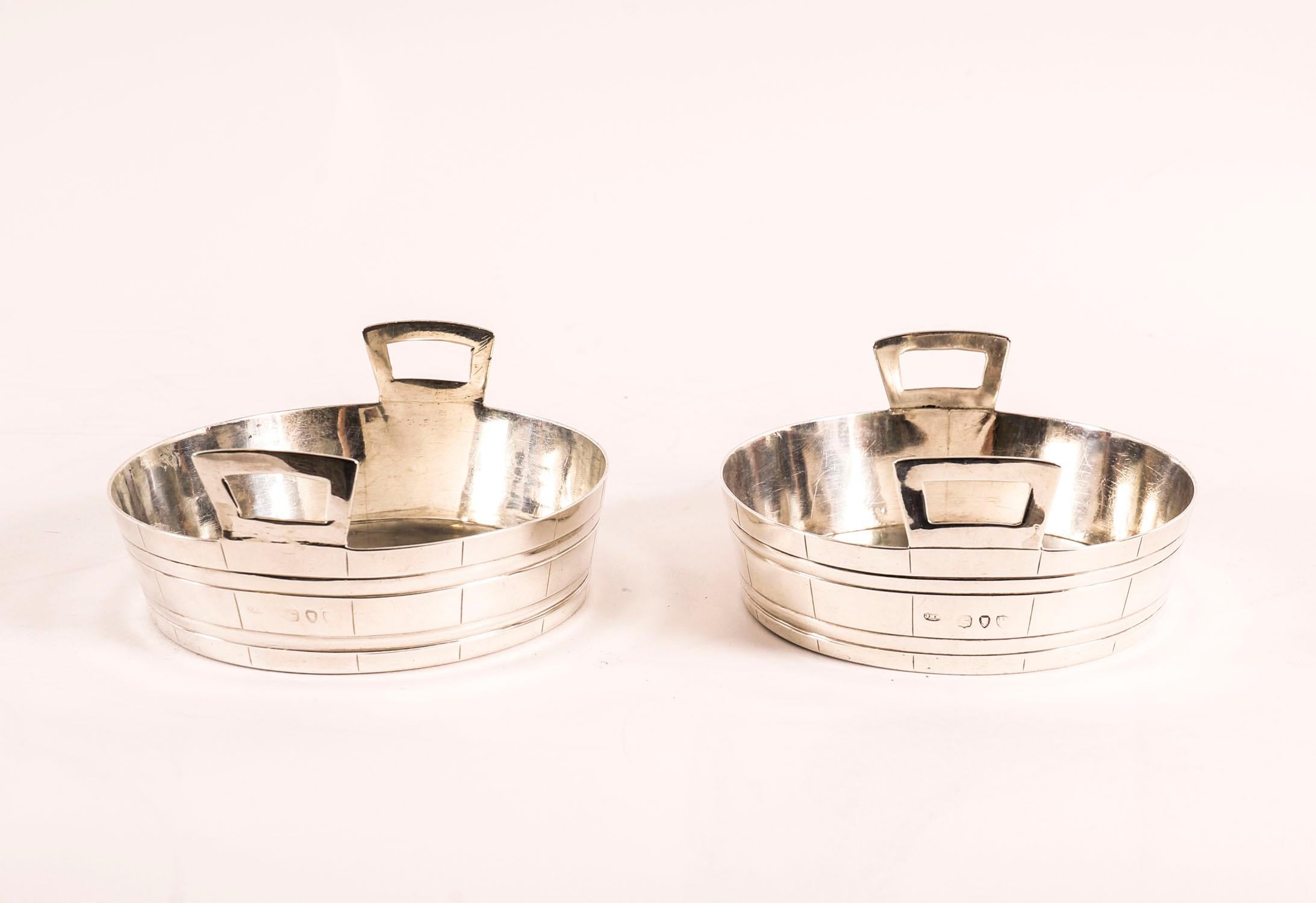 This is a very attractive pair of antique Victorian sterling silver dishes / coasters with hallmarks for London 1890.
 
They feature attractive faux-coopered decoration with a handle to each side.
 
Add an elegant touch to your next dining