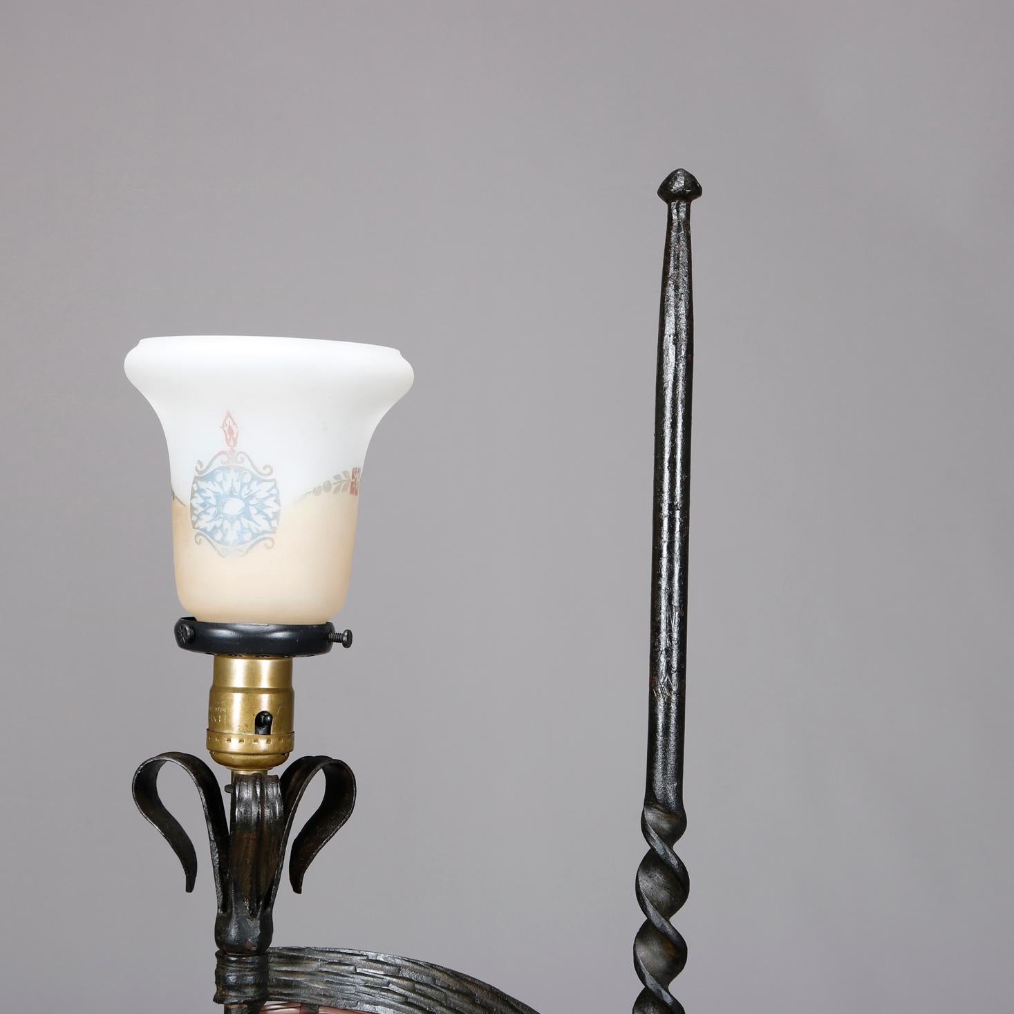 An antique pair of Arts & Crafts floor lamps in the manner of Samuel Yellin offer wrought iron construction with twisted spire form shaft having scrolled arms terminating in up and down lights, raised on tripod stylized legs, circa