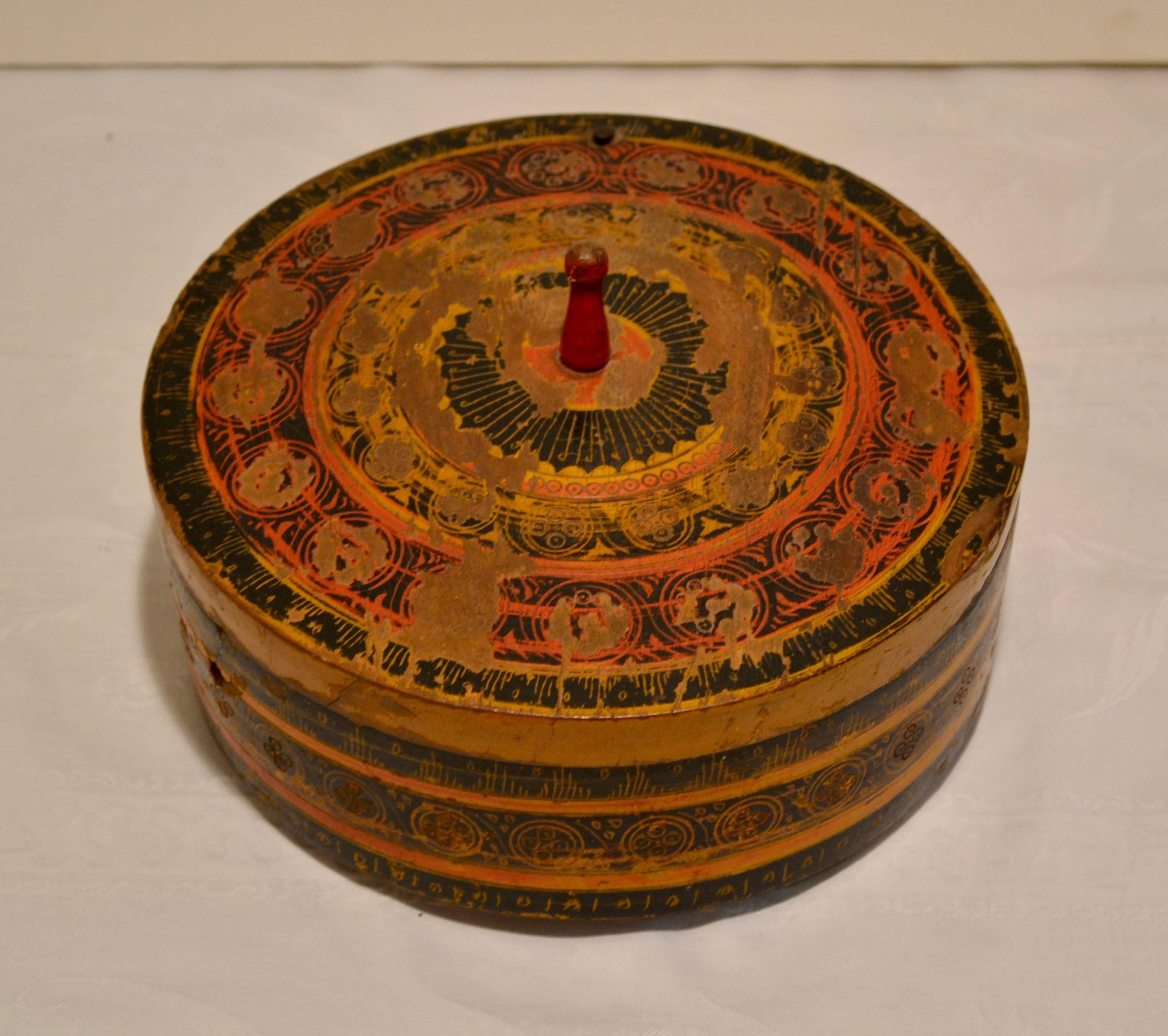 This is an unusual and hard to find Pakistani tribal spice box, hand-turned, with incised and hand-painted decoration in red gold and black. Larger than most pieces of its kind, the lid of this one pivots aside on a nail to reveal five hewn