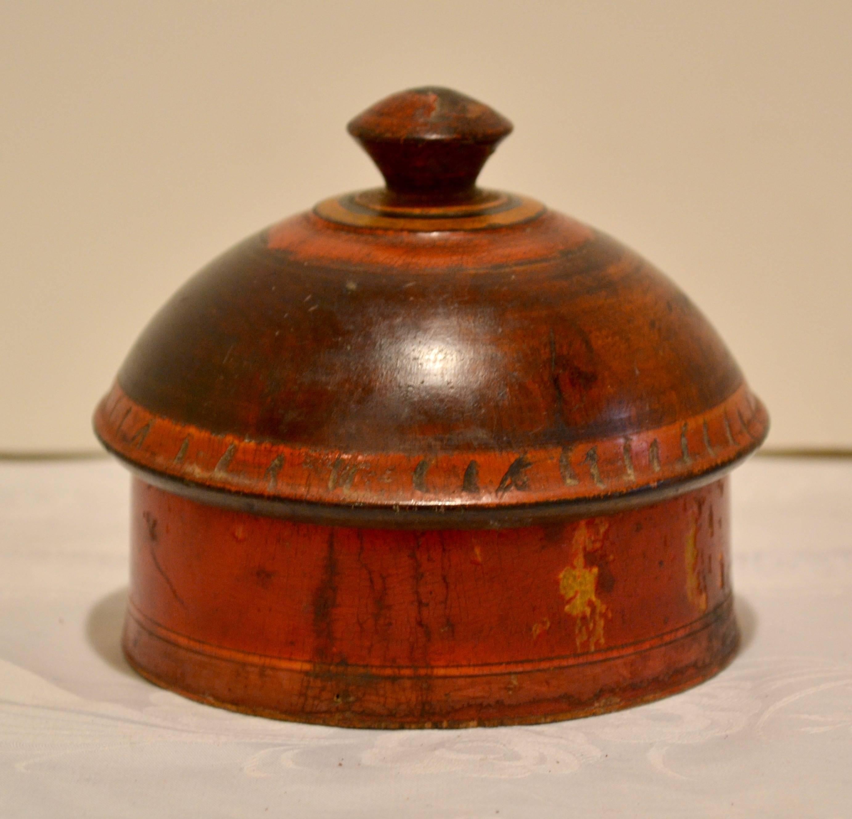 This is a delightful little hand-turned Pakistani tribal wooden spice box with a beautiful form and striking yet understated hand-painted design in red, gold, black and rich walnut. Both lid and box have a gentle flare to the rim and bottom. The lid