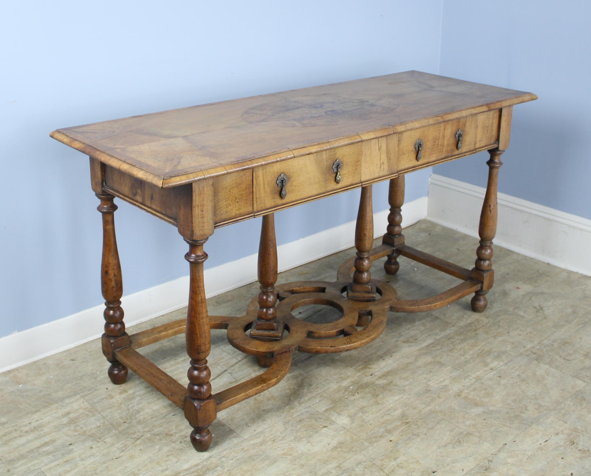 A splendid early pale walnut console or server with ornate turned legs and supports. The splendid book matched walnut veneer on top is eye-catching, with small areas of age appropriate wear. Two small drawers provide storage. Teardrop escutcheons