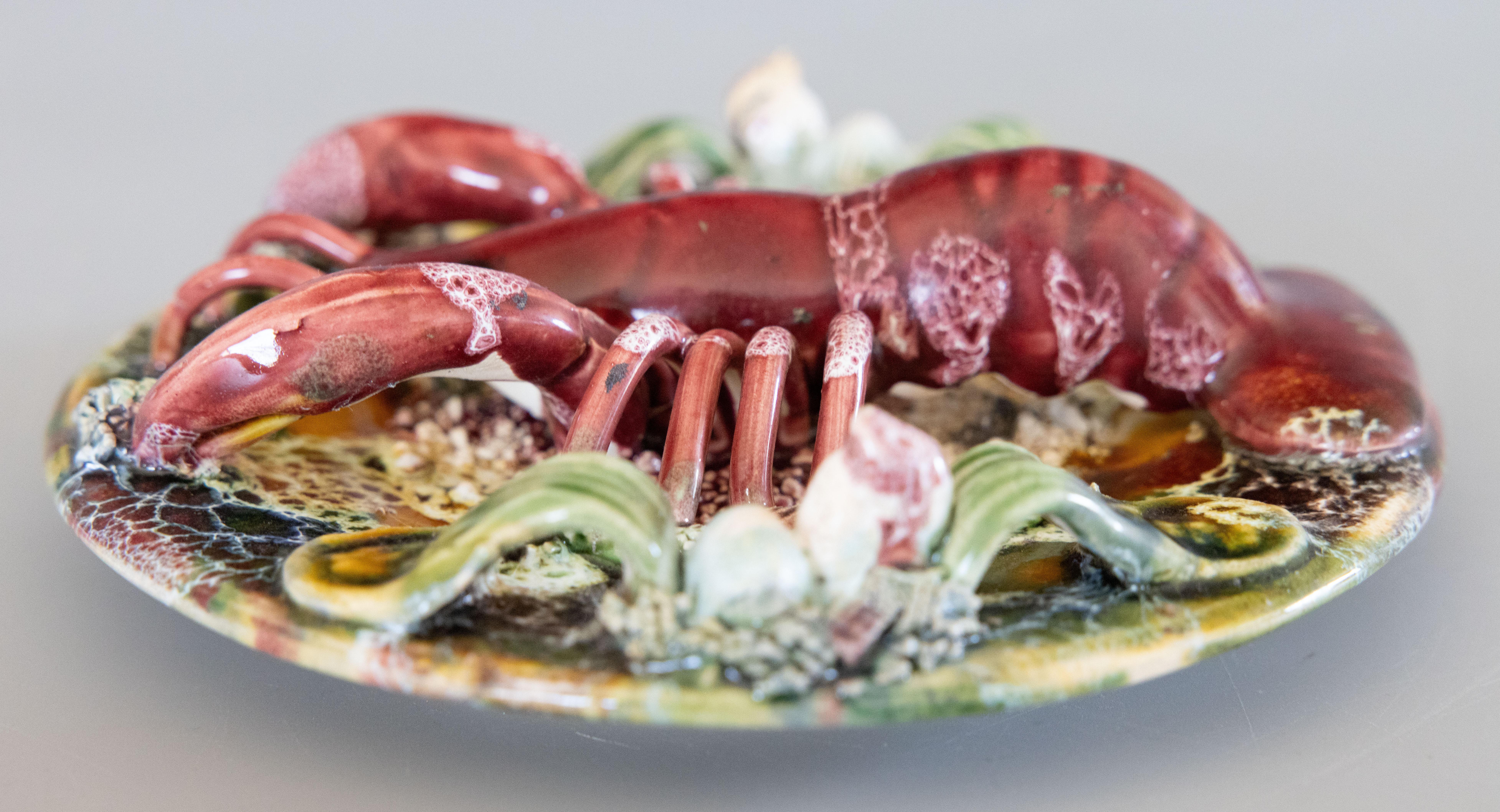 Magnifique assiette ancienne en majolique de Palissy avec un grand homard et d'autres crustacés. Le bord antérieur est percé pour la suspension. Circa 1920.