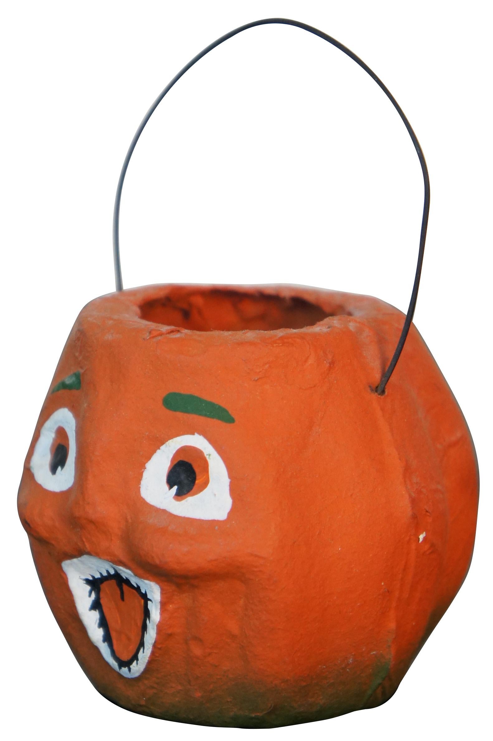 Antique paper mache miniature jack-o-lantern shaped candy bucket with painted face and wire handle.
      