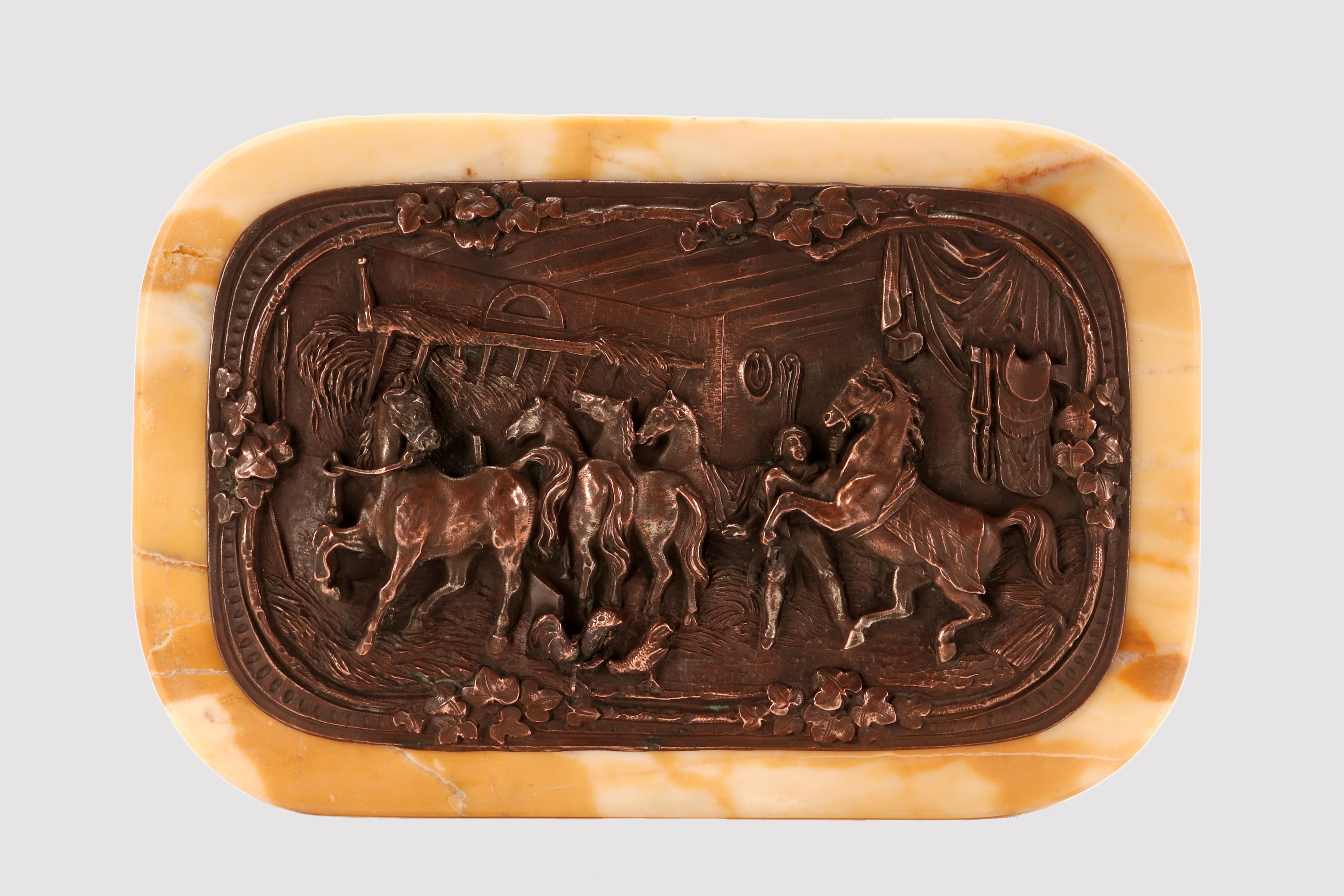 Antico fermacarte o pressa per carta inglese, in marmo giallo di Siena, di forma rettangolare con una placca rettangolare in rame sbalzato e cesellato raffigurante un gruppo di cavalli in una stalla con galline. Regno Unito, fine del XIX secolo.