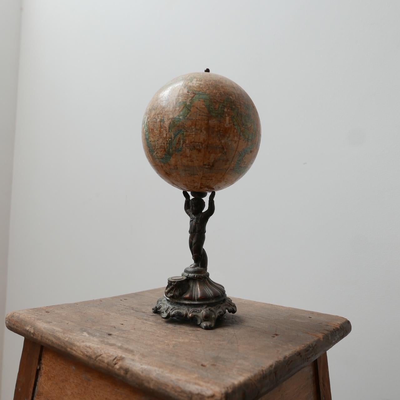 A papier-mache antique globe. 

c1900s, Germany. 

By Ludwig Julius Heymann, Berlin. 

An integrated compass with a young figure of a boy raising the world above his head.

Wear commensurate with age but genererally good condition.