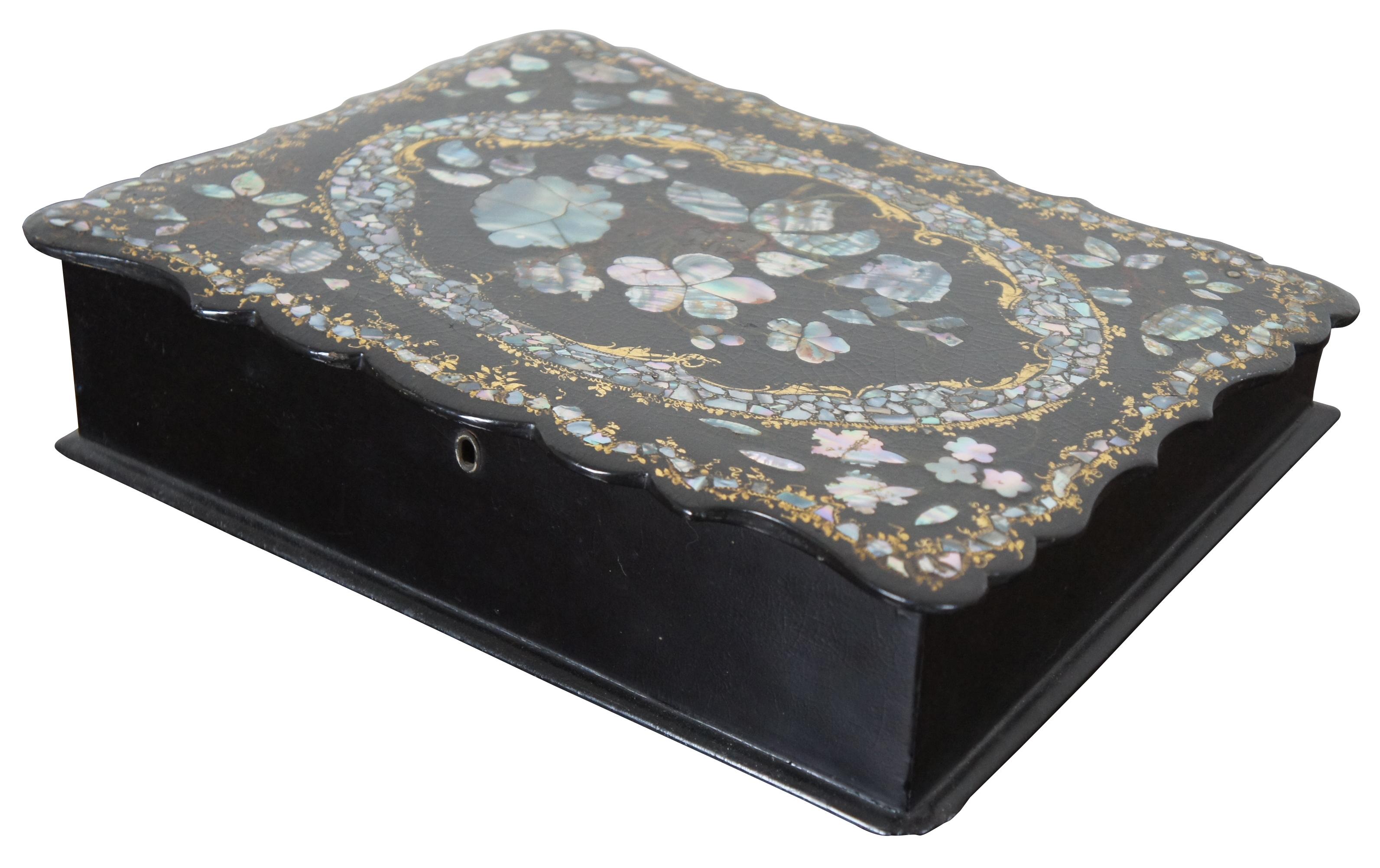 Antique black lacquered, scalloped edge writing slope with gold painted accents setting off a floral inlay of mother of pearl. Interior flat surface is lined with red velvet and includes three compartments for pens and paper. Original lock hardware