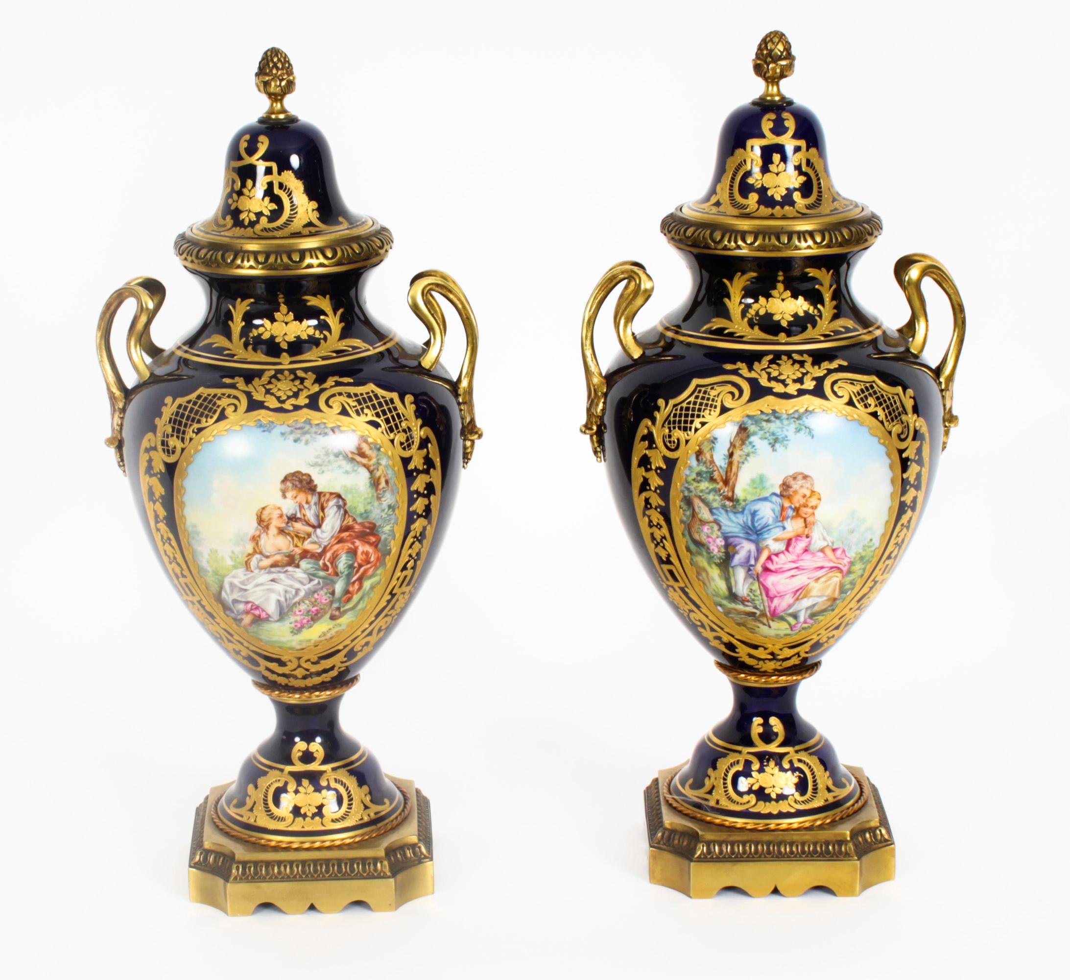 A beautiful and monumental Paris porcelain ormolu mounted three piece garniture set with hand-painted scenes and delicate gilt decoration, Circa 1900 in date. 
 
The set comprising a pair of lidded vases and a two handled oval bowl. The Royal Blue
